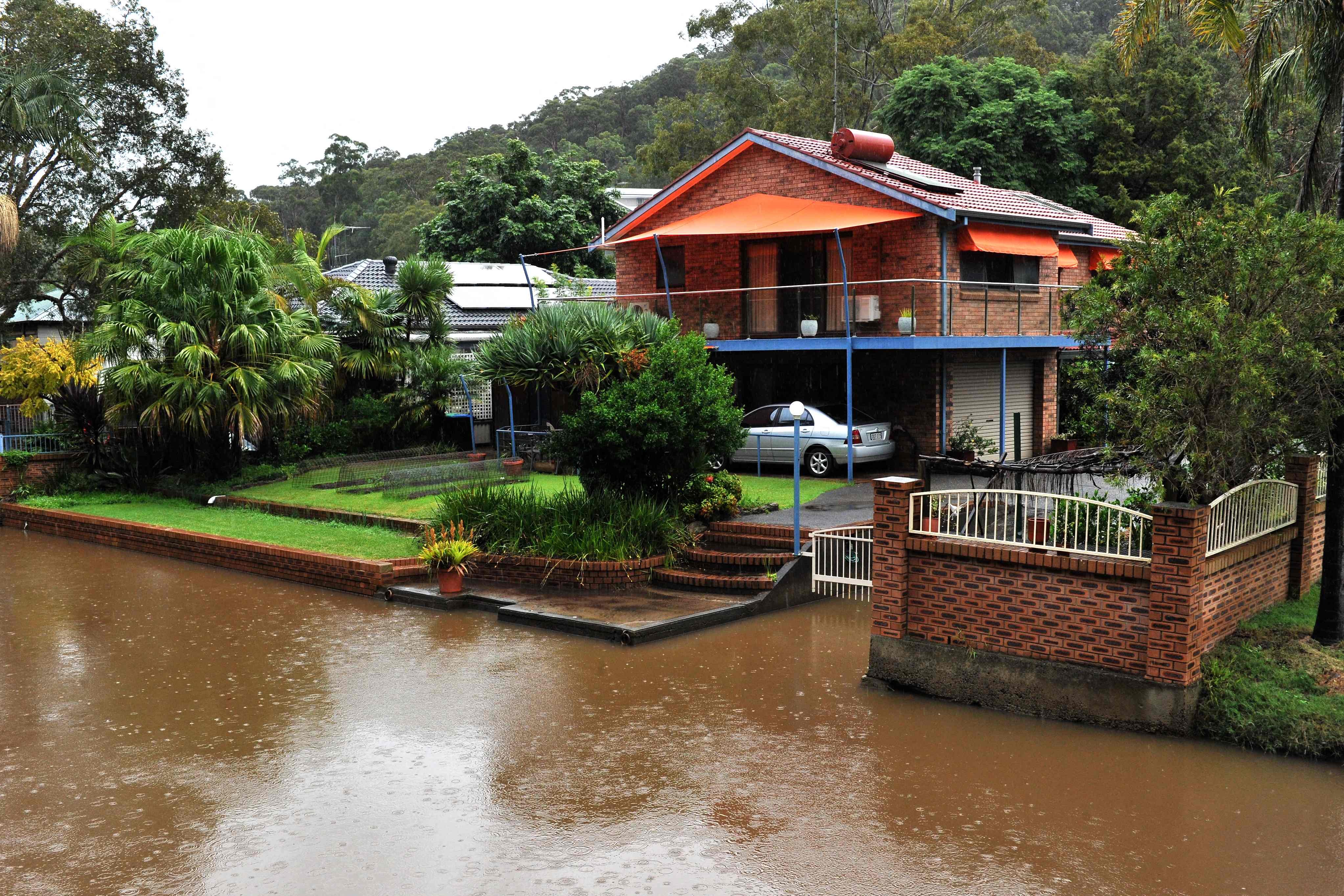 Houses are seen on the bank of overflowing Woronora river on Thursday as inclement weather triggered evacuation orders in several suburbs of Sydney’s south and southwest. Photo: AFP