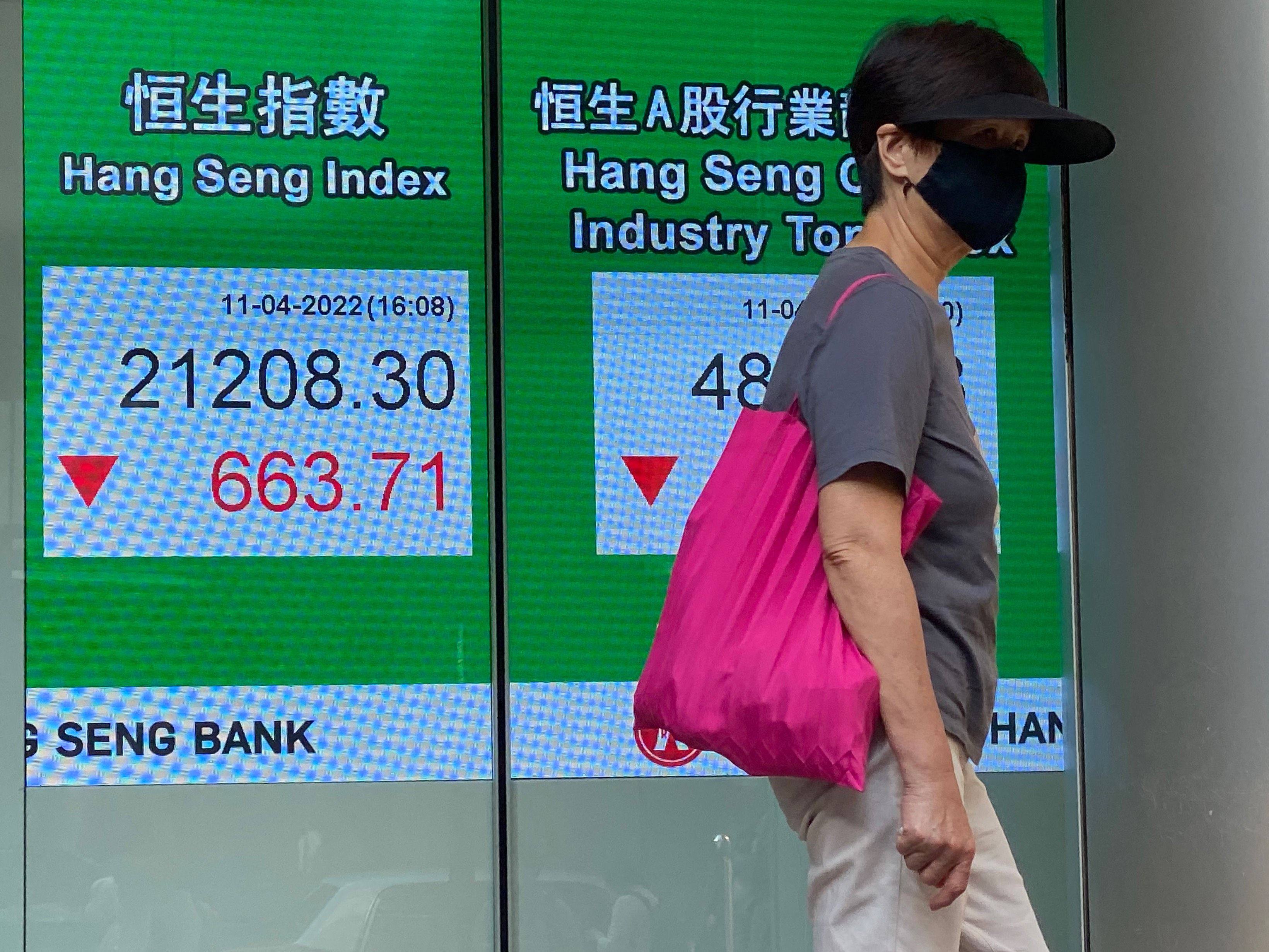 A woman walks past a sign showing the Hang Seng Index in Hong Kong on April 11. Photo AFP
