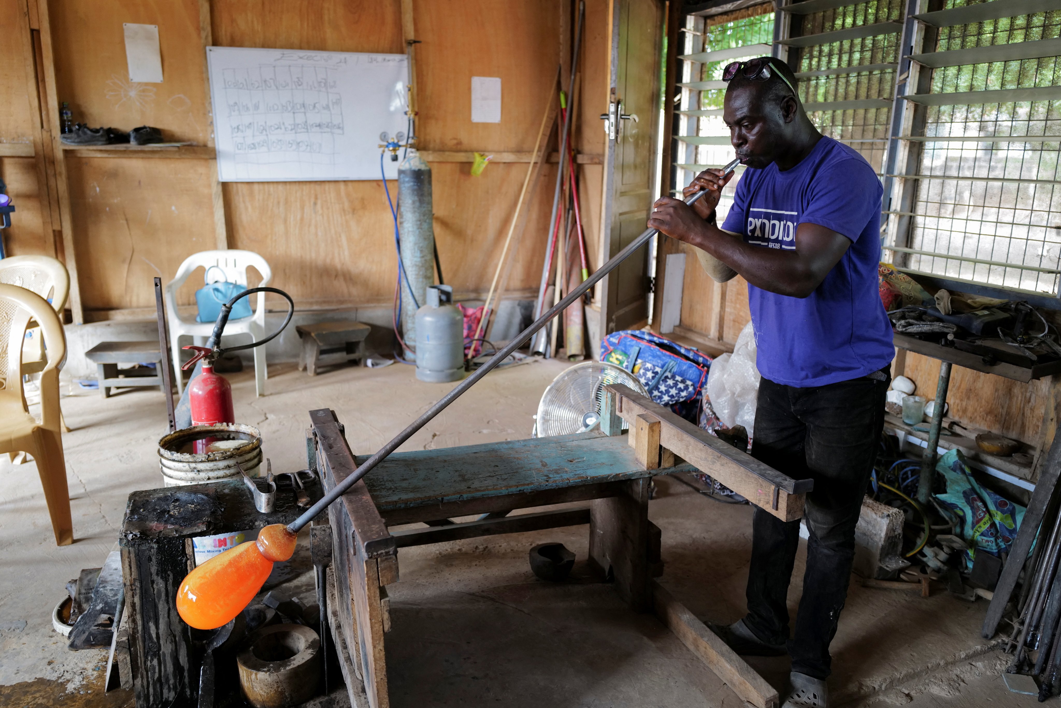 Ghanaian glassblower Michael Tetteh, 44, blows glass at his glassware manufacturing workshop in Krobo Odumase, Ghana March 15, 2022. Picture taken March 15, 2022. REUTERS/Francis Kokoroko
