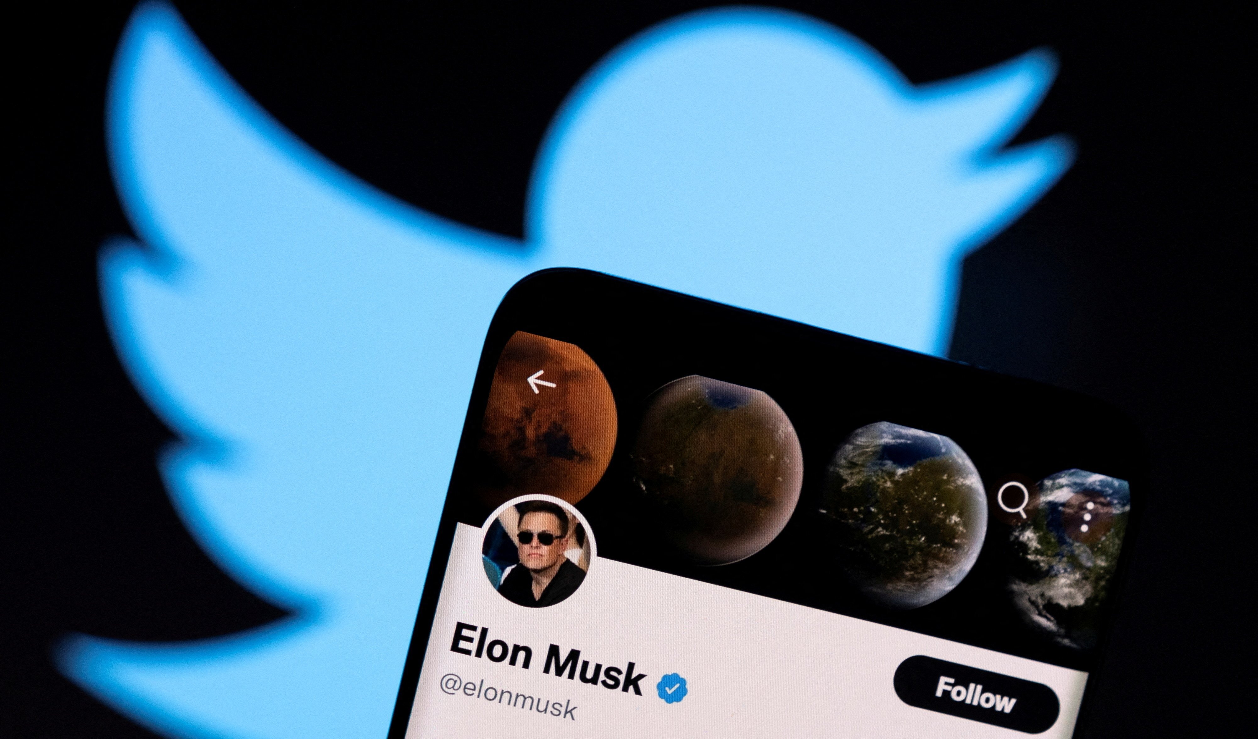 Elon Musk’s Twitter account is seen on a smartphone in front of the Twitter logo in this photo illustration taken April 15, 2022. Photo: Reuters