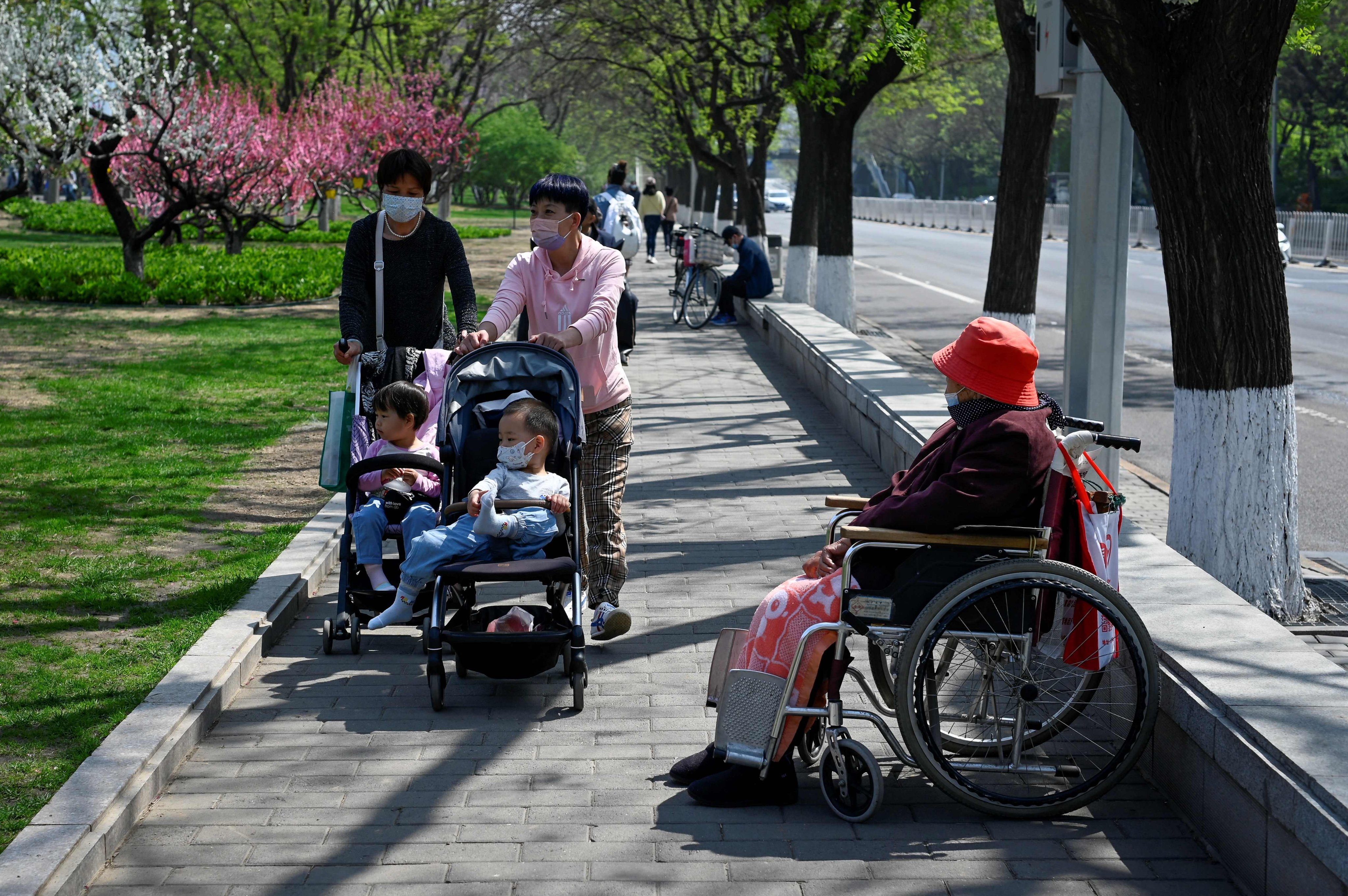 Two women push strollers past an elderly woman in Beijing on April 19. The growing number of elderly in China will create a far-reaching financial burden on local governments. Photo: AFP