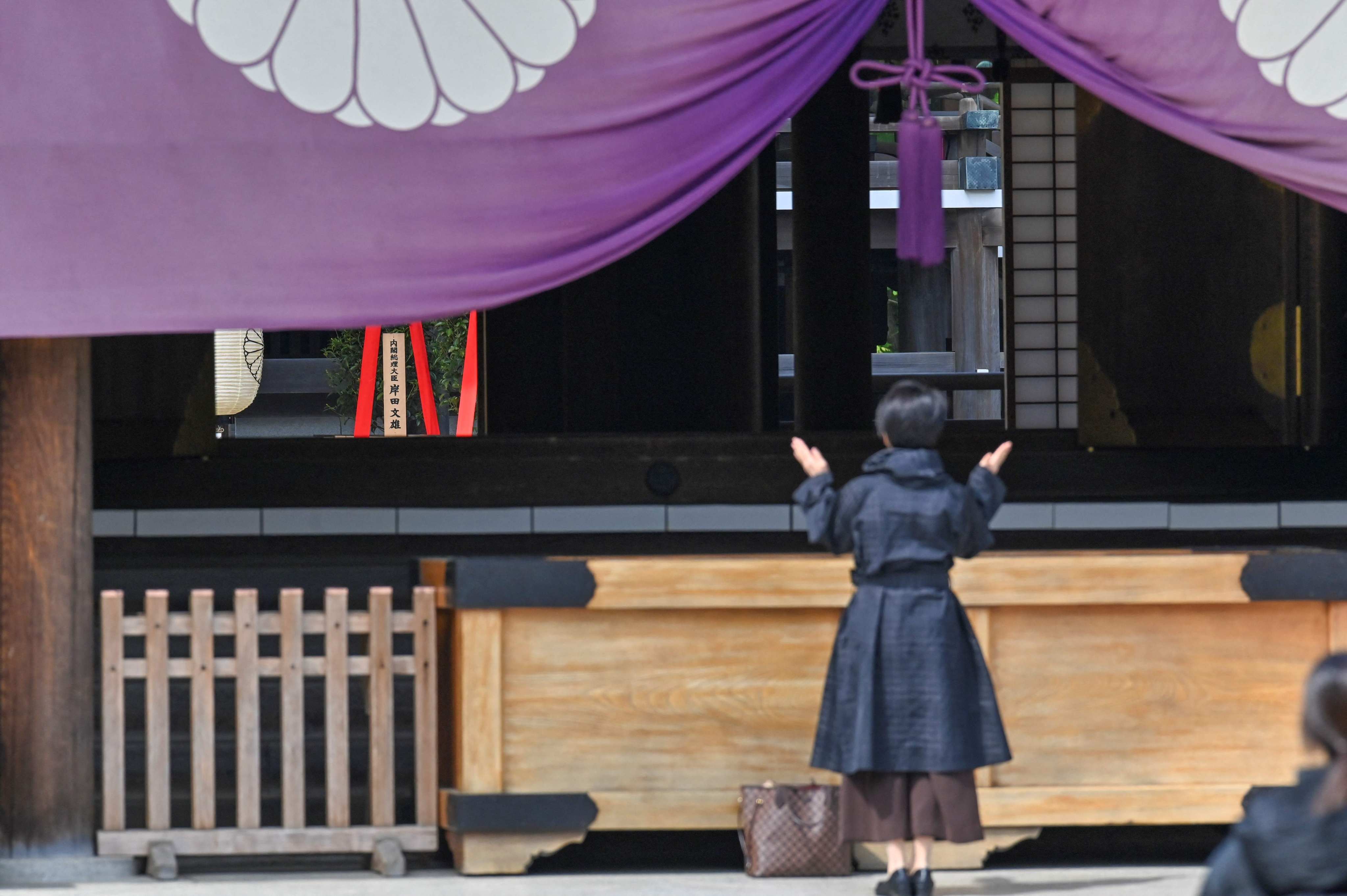A woman prays in front of a ritual offering sent to the controversial Yasukuni shrine by Japanese Prime Minister Fumio Kishida in Tokyo on Thursday. Photo: AFP

