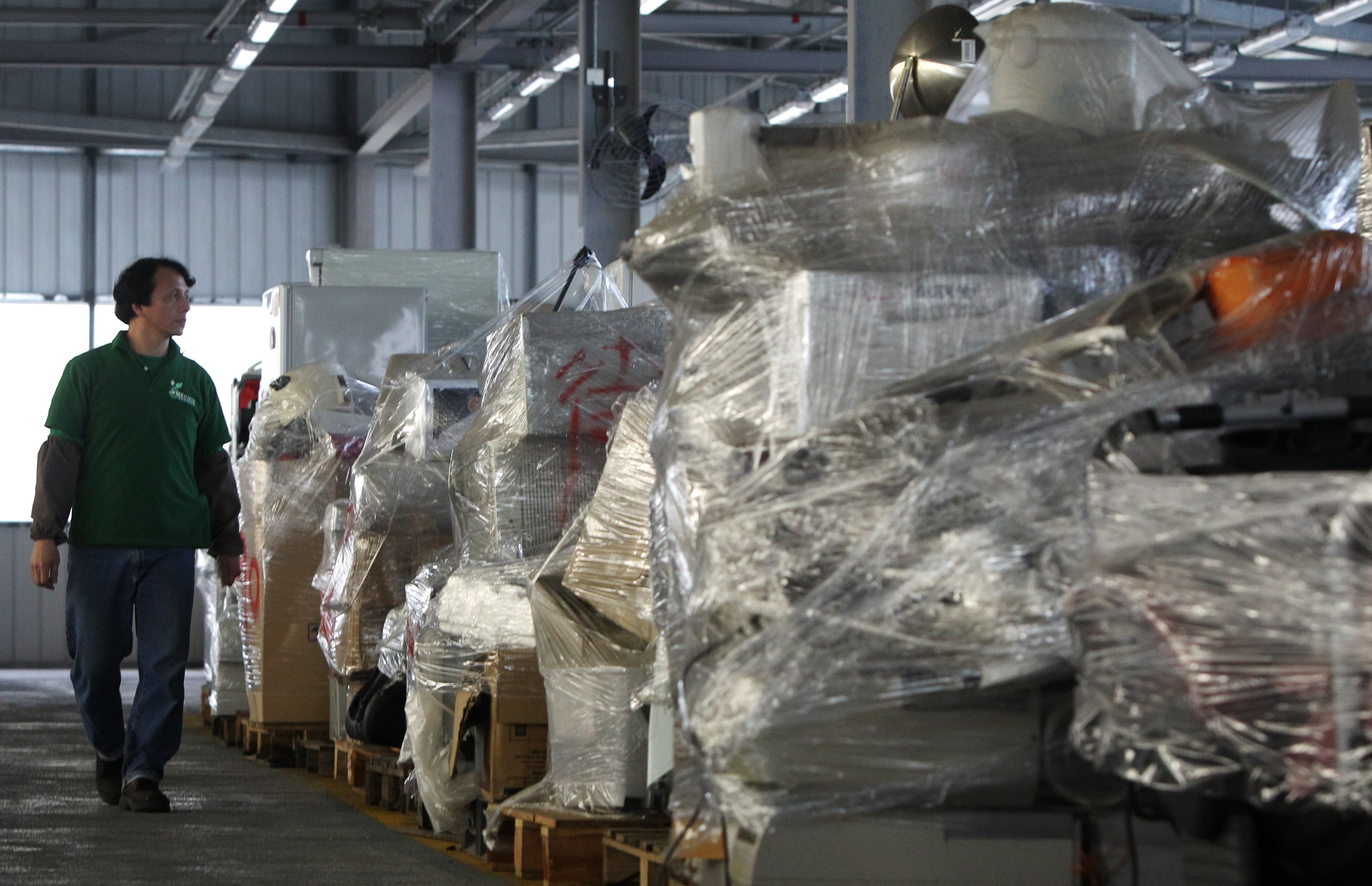 A worker of WEEE Recycling Centre walks past old electrical appliances collected at EcoPark WEEE Recycling Centre in Hong Kong’s Tuen Mun district on 27 January 2011. Photo: SCMP