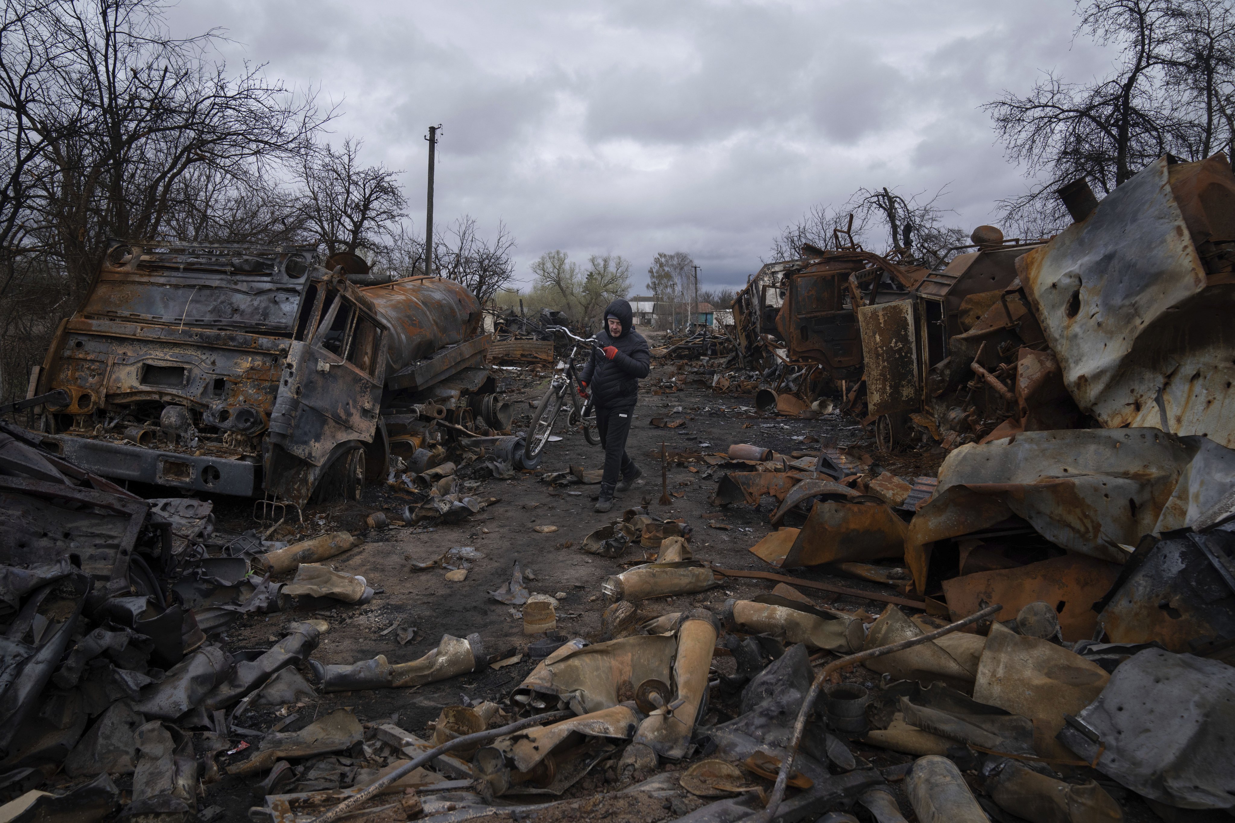 A man carries a bicycle along a street filled with destroyed Russian military vehicles near Chernihiv, Ukraine, on April 17. Photo: AP