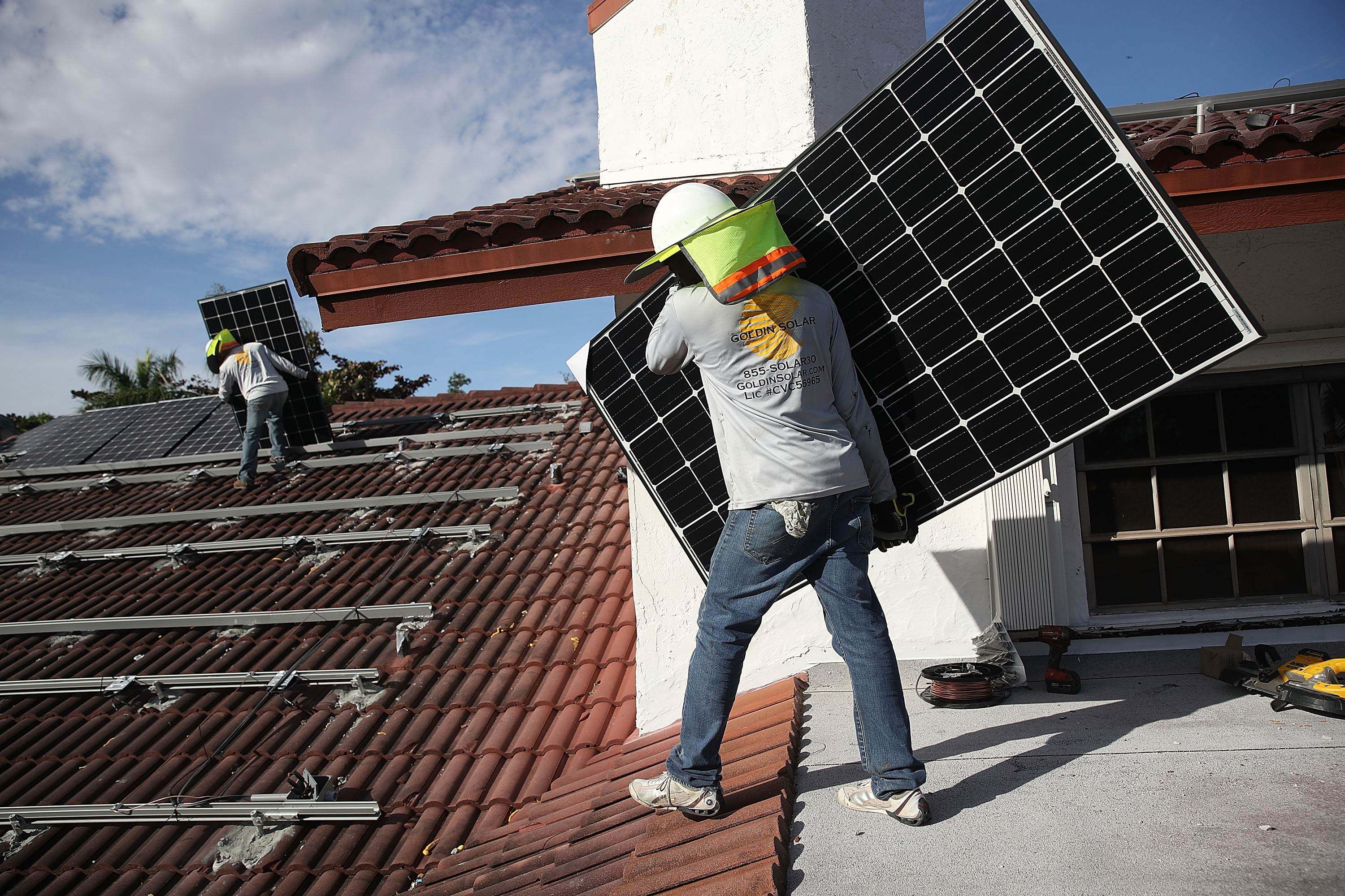 Workers install solar panels on the roof of a home in Palmetto Bay, Florida, US, on January 23, 2018. Photo: AFP