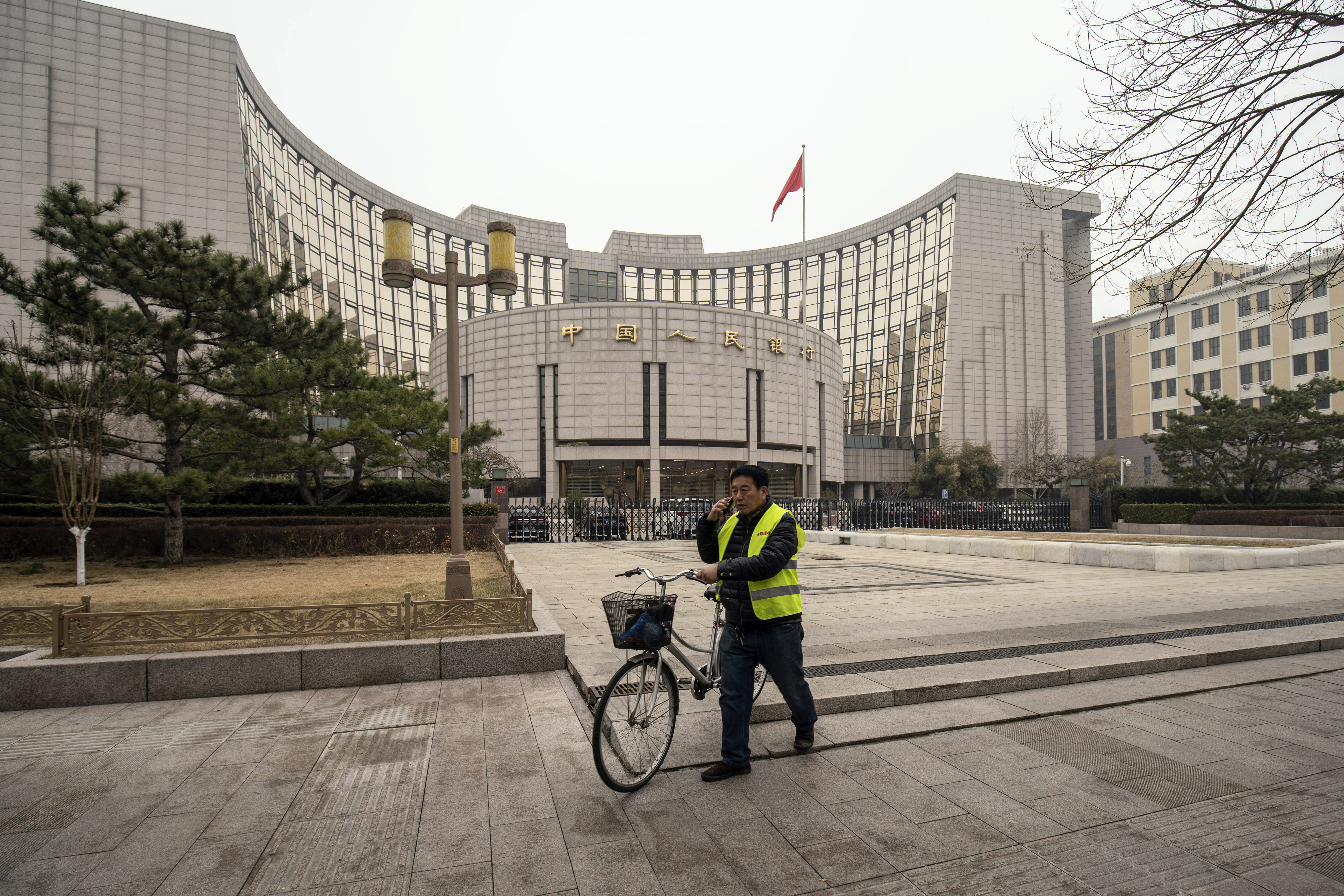 A person pushes a bike past the People’s Bank of China (PBOC) building in Beijing March 4, 2021. The bank’s reduction of reserve ratios in the first quarter of 2022 reduced costs for state-controlled banks. Photo: Bloomberg