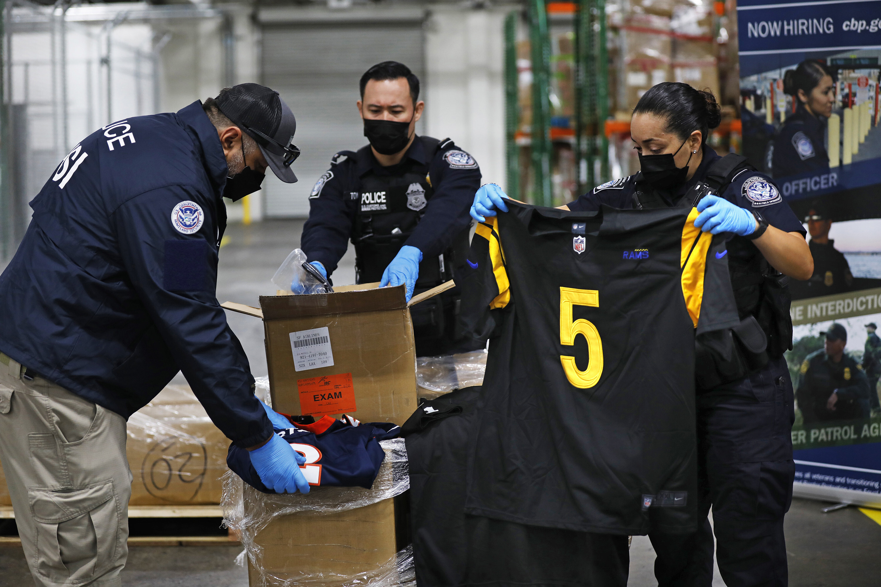 US Customs and Border Protection officers open boxes of counterfeit goods the agency has recovered, during a news conference in Los Angeles on Feb. 4, 2022, ahead of Super Bowl LVI. Photo: Los Angeles Times/TNS