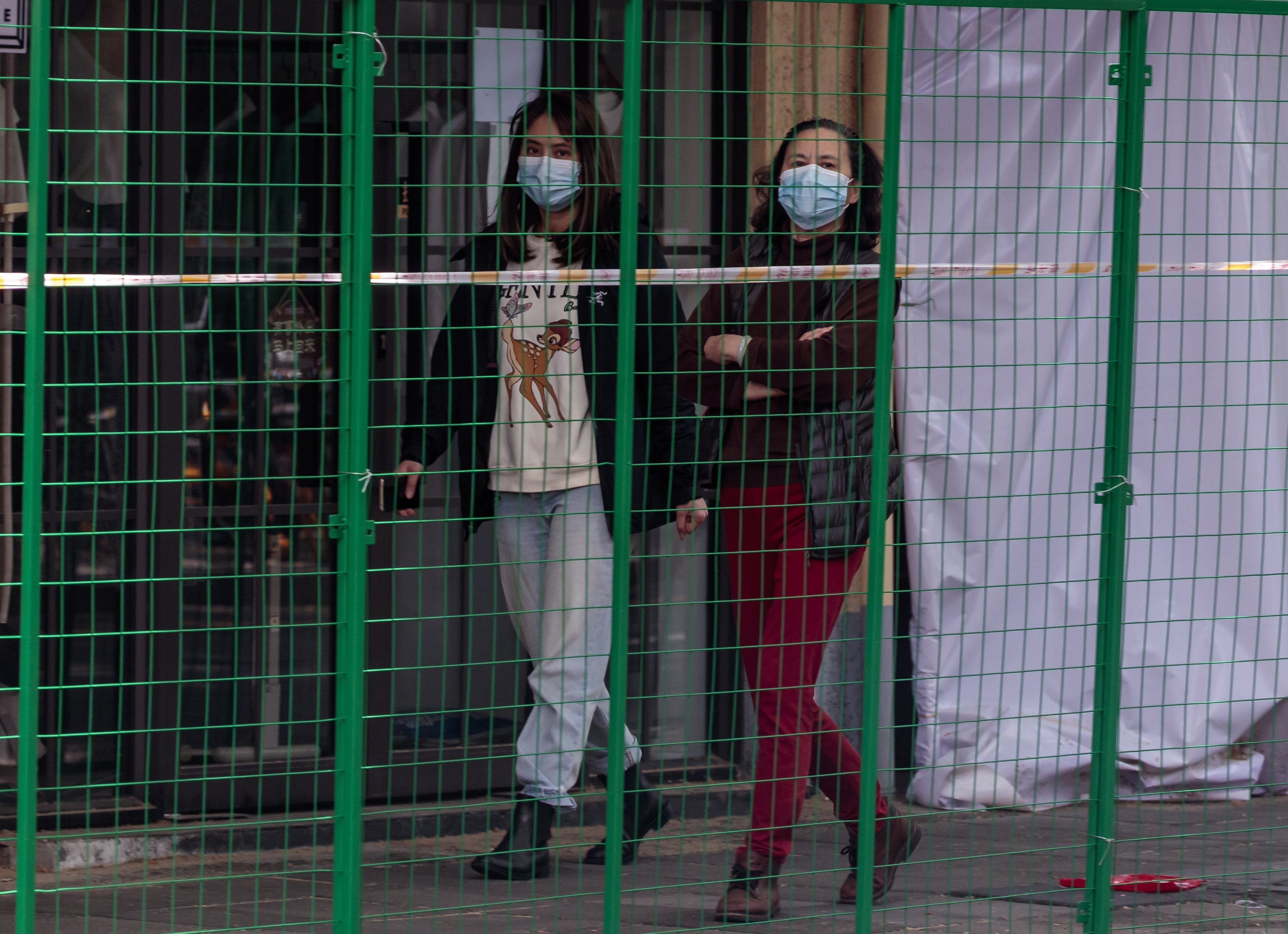 People walk next to the fence installed to block out a quarantined area in Shanghai. Photo: EPA-EFE