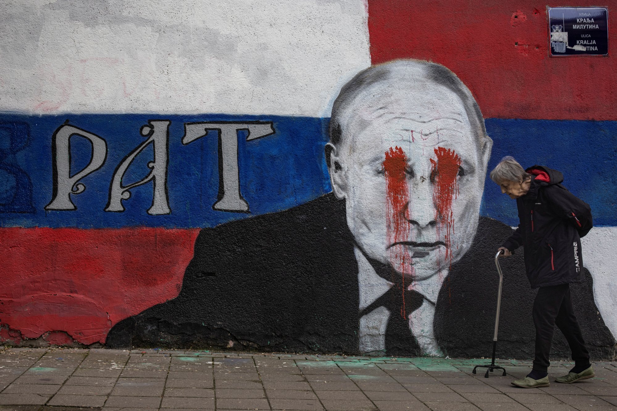 A person walks next to a mural of Russian President Vladimir Putin, which has been vandalised with red paint and the word “War” written instead of the original text reading “Brother”, in Belgrade, Serbia on Friday. Photo: Reuters