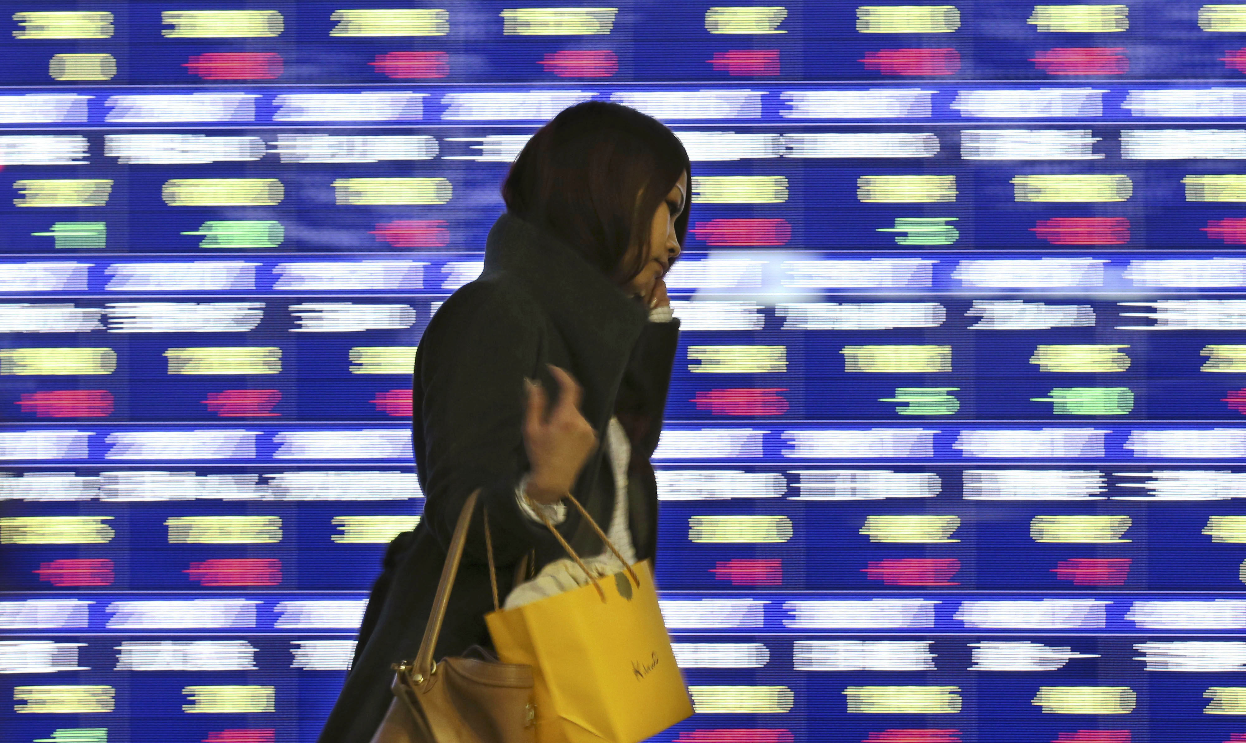 A woman walks past an electronic stock board in Tokyo. Even though much airtime has been given to criticising gender inequality at work, change has been slow. Photo: AP