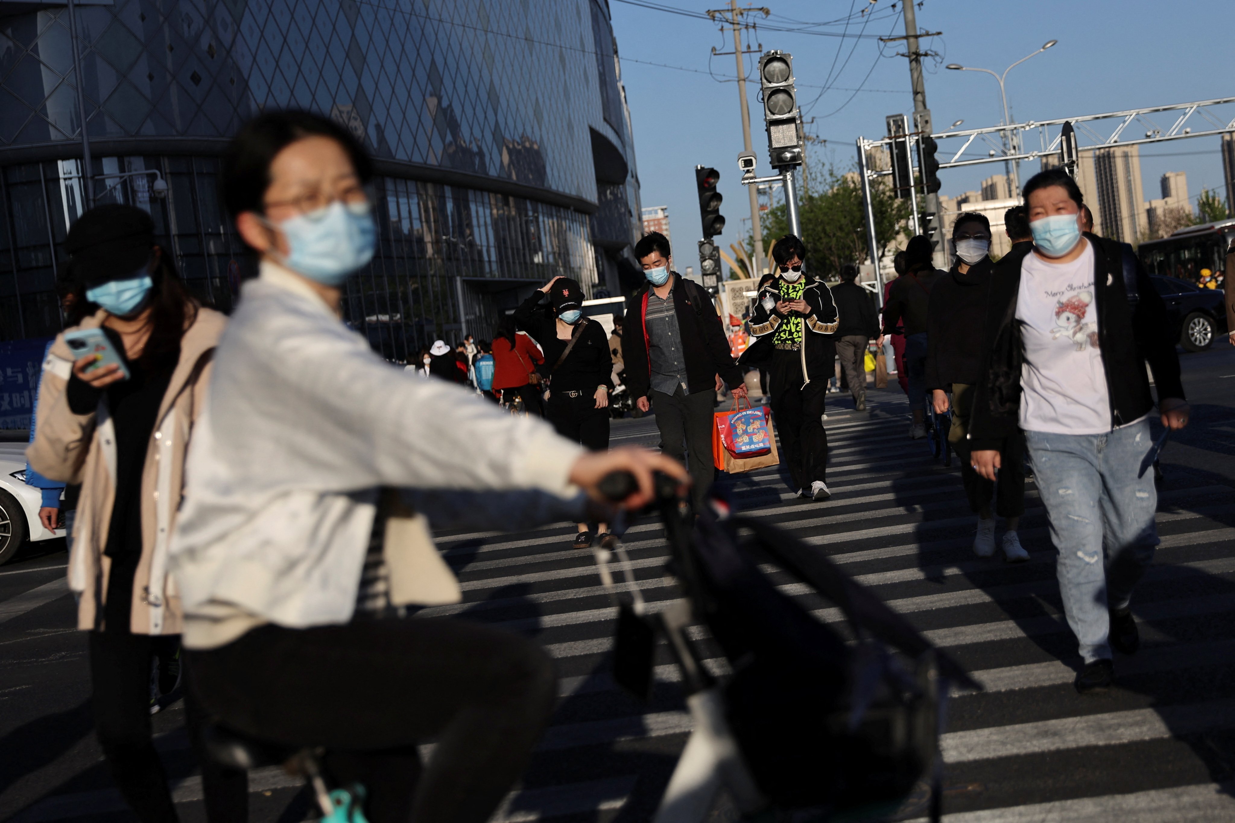 People wearing face masks to prevent the spread of Covid-19 walk across a street near a shopping mall in Beijing on April 15. Photo: Reuters