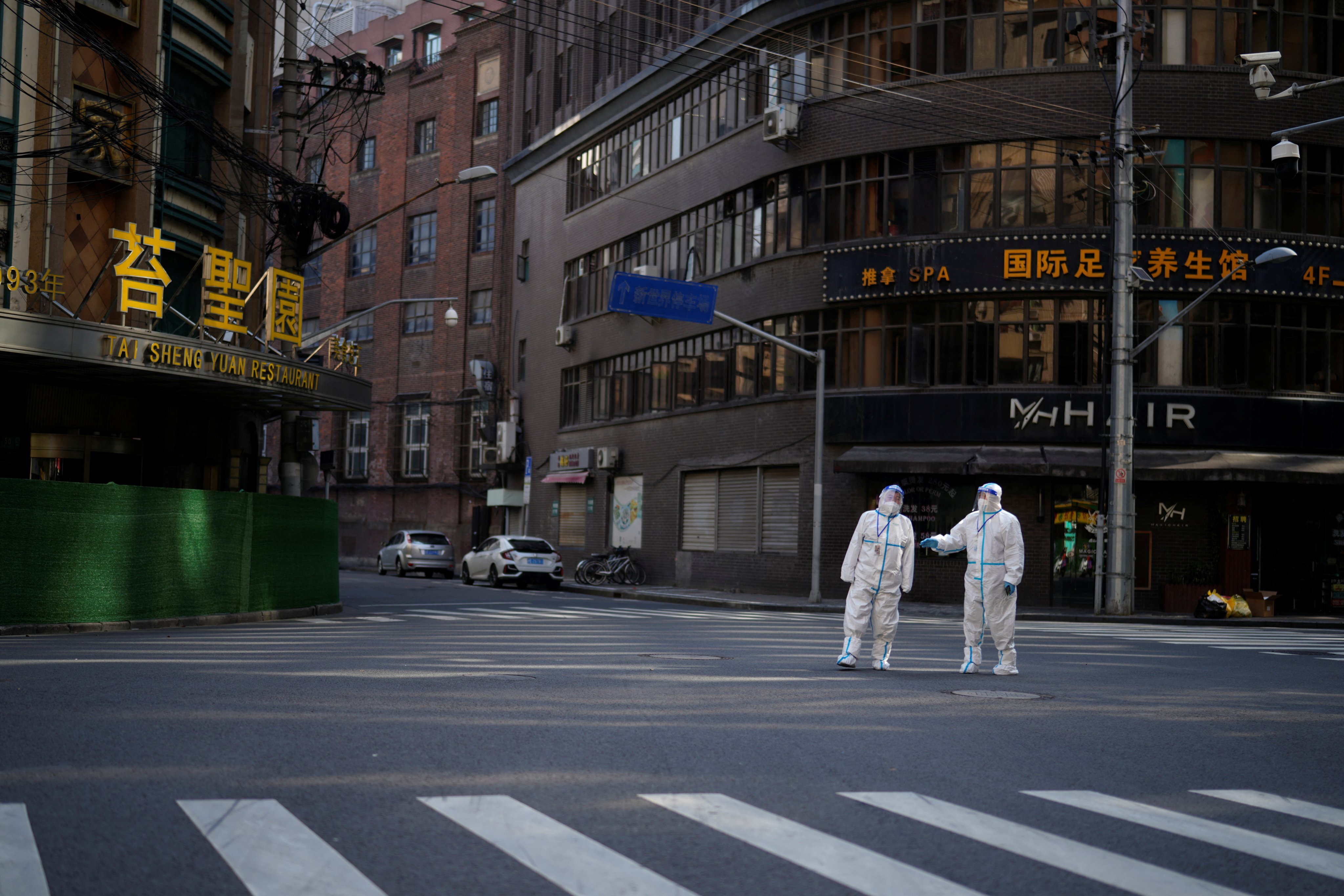 Workers in protective suits keep watch on a street during a lockdown in Shanghai on April 16. Photo: Reuters