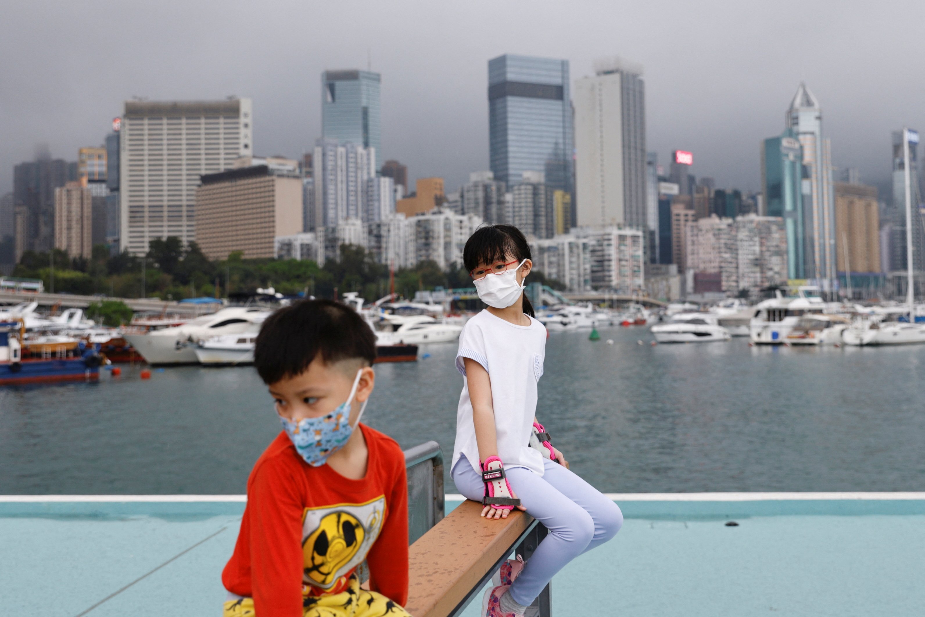 Children sit in front of Victoria Harbour during Hong Kong’s fifth wave of the coronavirus pandemic. Photo: Reuters