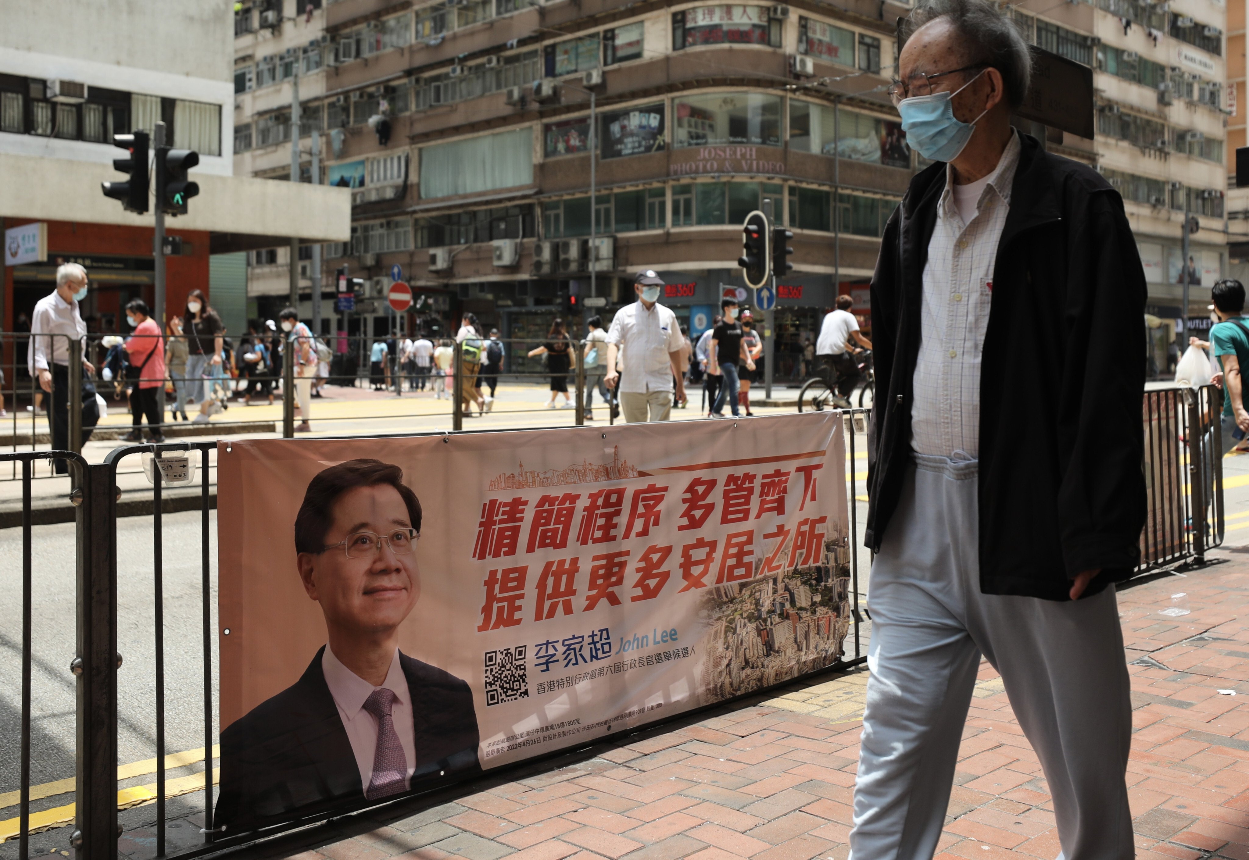 A man passes a campaign poster for chief executive candidate John Lee in North Point on April 29. Photo: Xiaomei Chen