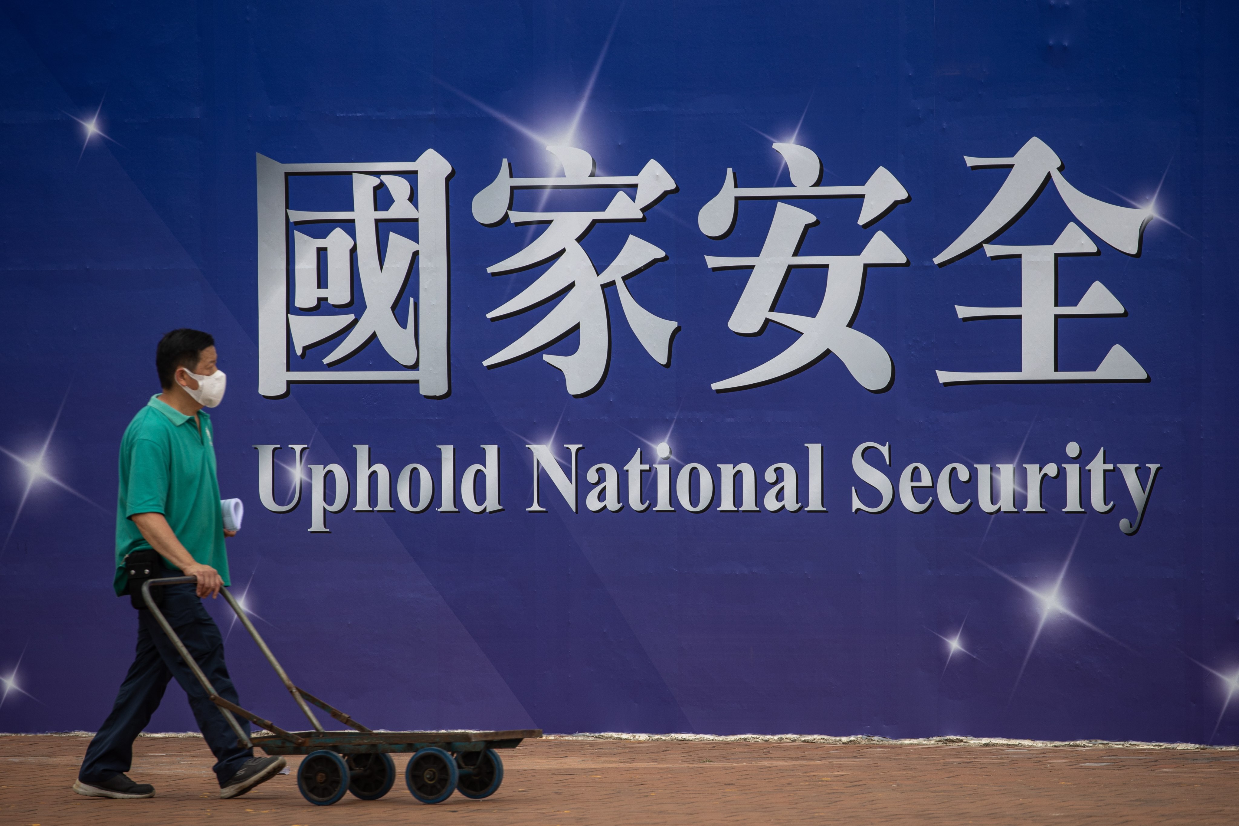 A man pushes a trolley past a banner promoting the national security law in Hong Kong on April 13.  Photo: EPA-EFE
