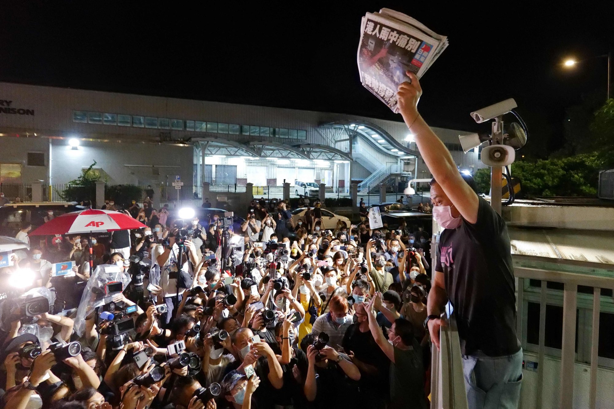 This file photo taken on June 24, 2021 shows an Apple Daily journalist holding freshly-printed copies of the newspaper’s last edition to be distributed to supporters gathered outside their office in Hong Kong, as the tabloid was forced to close after 26 years. Photo: AFP