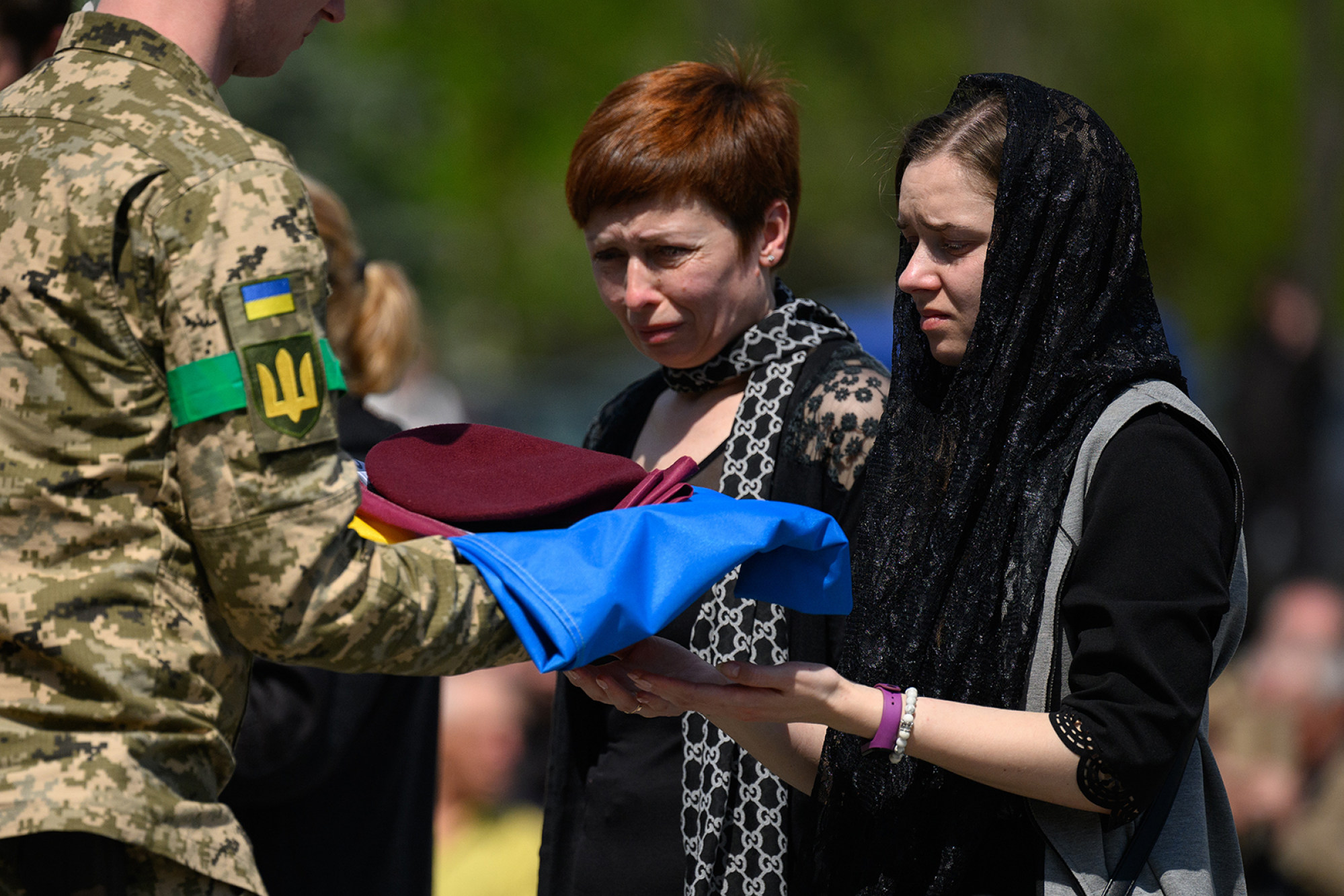 Oksana Malevsky receives the flag from the coffin of her husband Alexander Malevsky during the simultaneous burial of three soldiers in Lviv on Friday. Photo: TNS