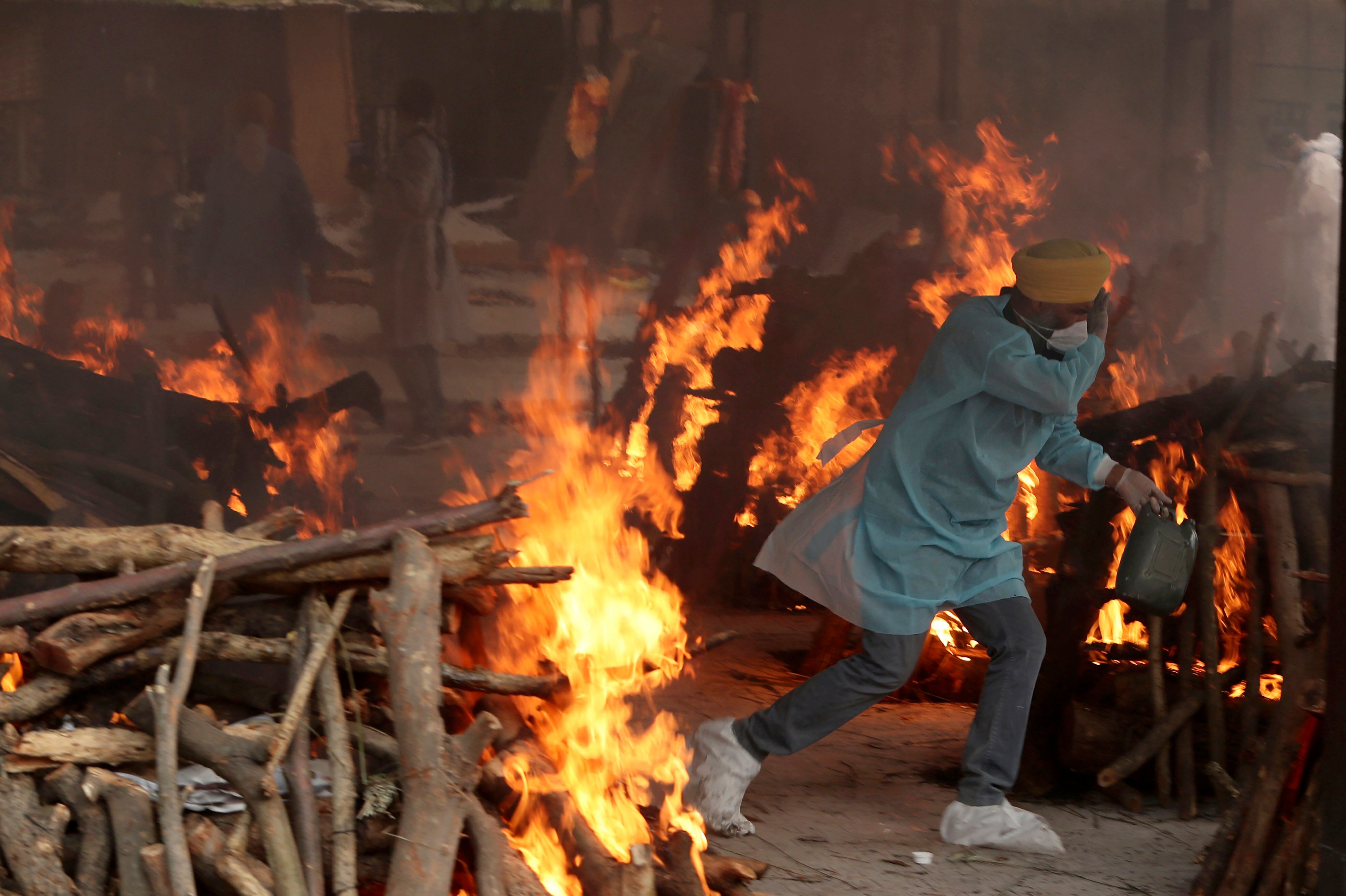 A volunteer runs to avoid the heat from the funeral pyres of Covid-19 victims at a crematorium in Jammu, India, in May 2021. Photo: AP