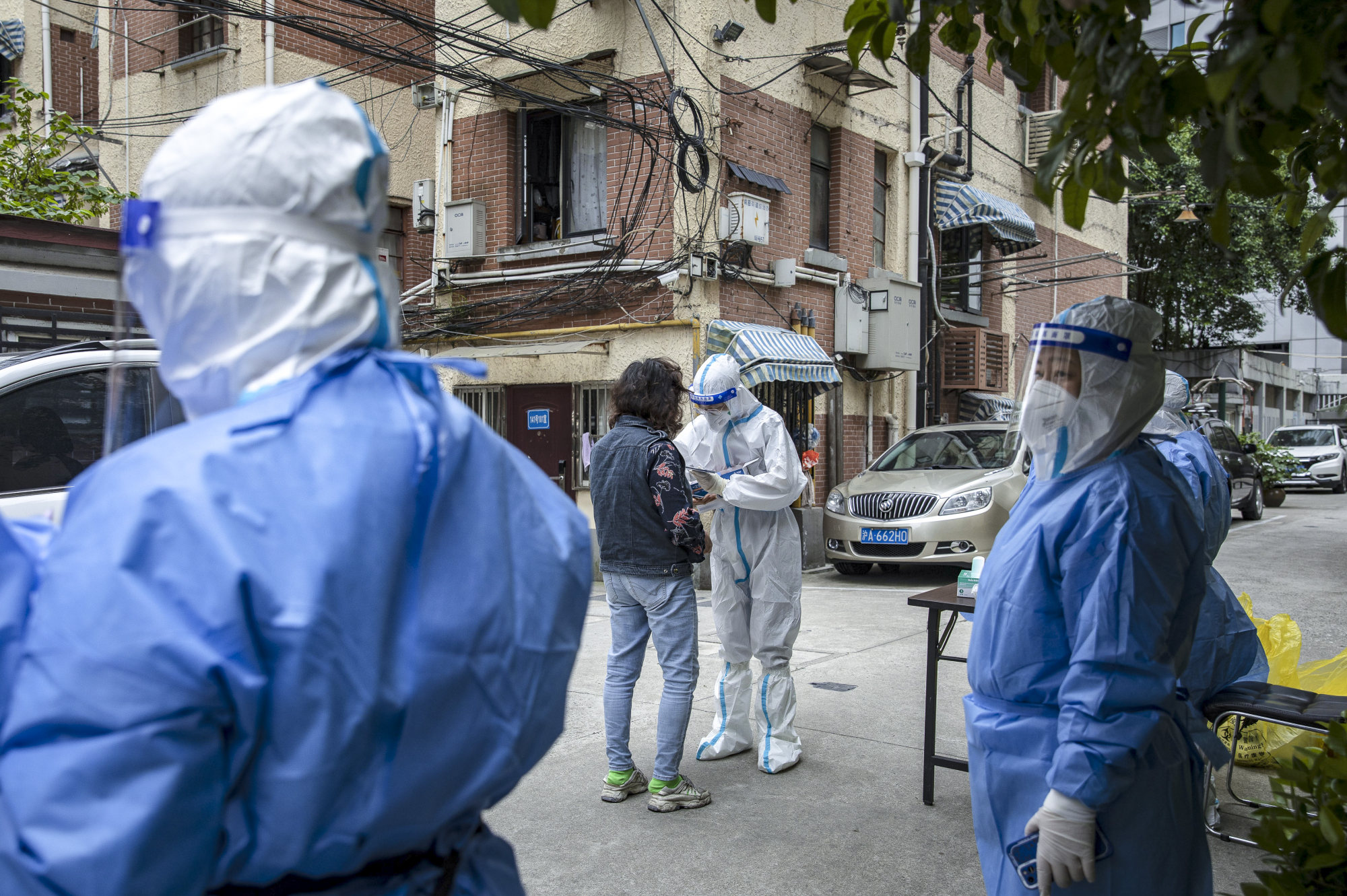 Health workers and volunteers stand guard at a residential compound as a resident arrive at a Covid-19 testing station in Shanghai on Monday, May 9, 2022. Photo: Bloomberg.
