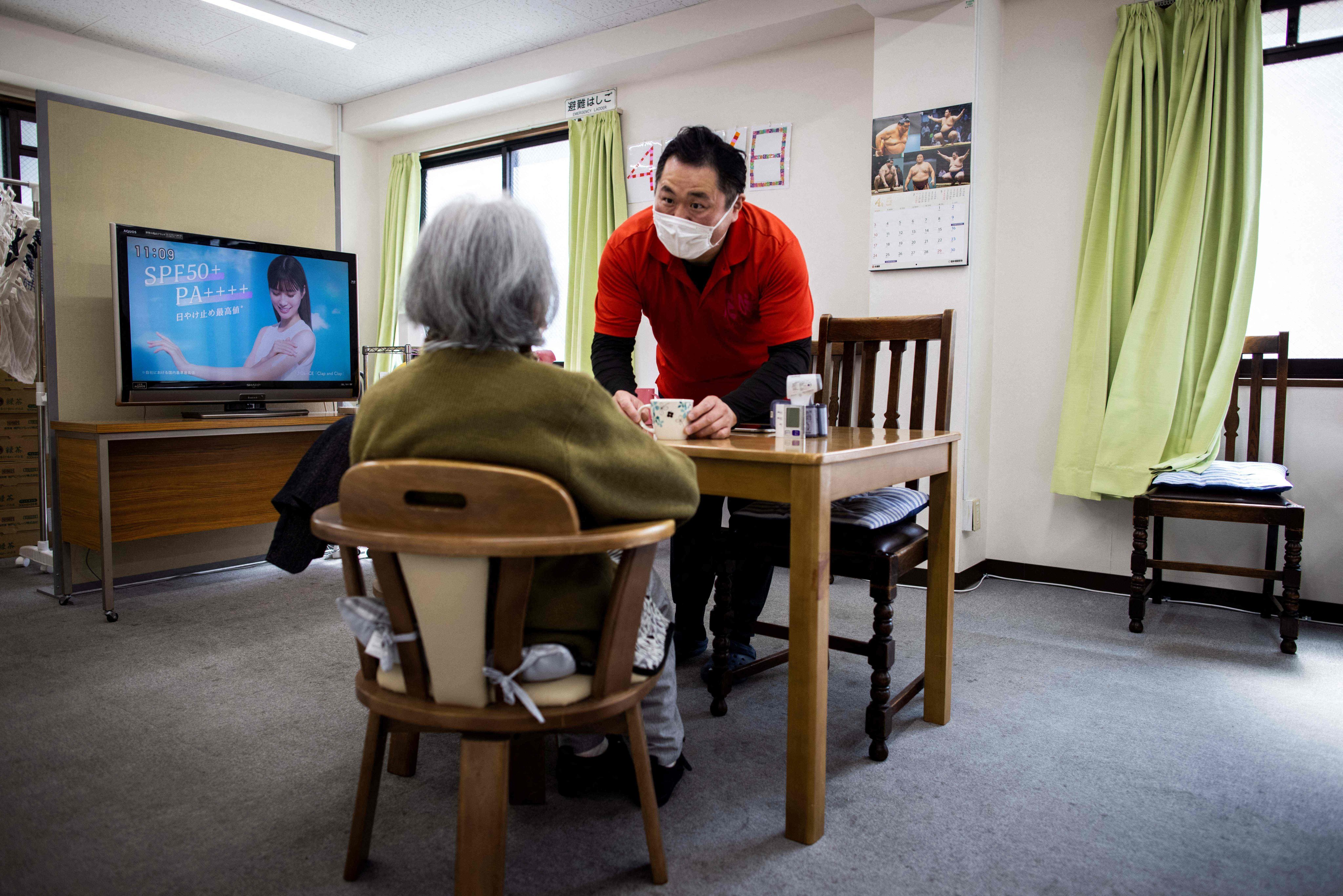 Retired Japanese sumo wrestler Hiromi Yamada, who competed under the name Wakatoba, takes care of an elderly woman at the Hanasaki daycare centre in Tokyo on April 6. Countries around the Asia-Pacific are in dire need of care staff, leading them to think outside the box in addition to importing labour from overseas. Photo: AFP