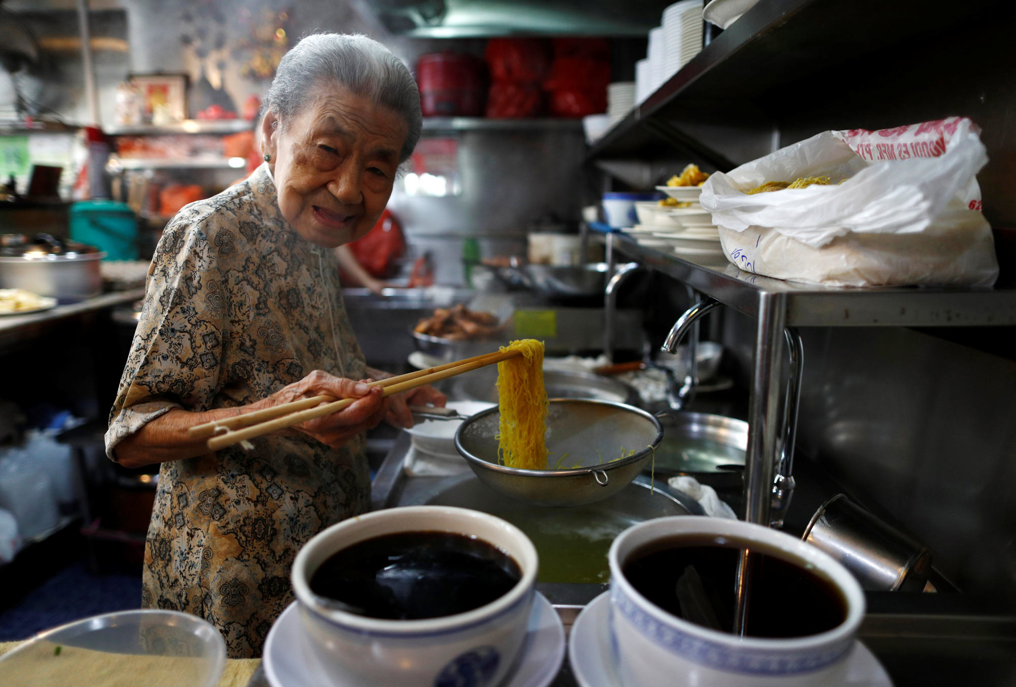 A hawker prepares noodles at her shop in Singapore. The price of wheat flour has increased by up to 15 per cent in recent months. Photo: Reuters