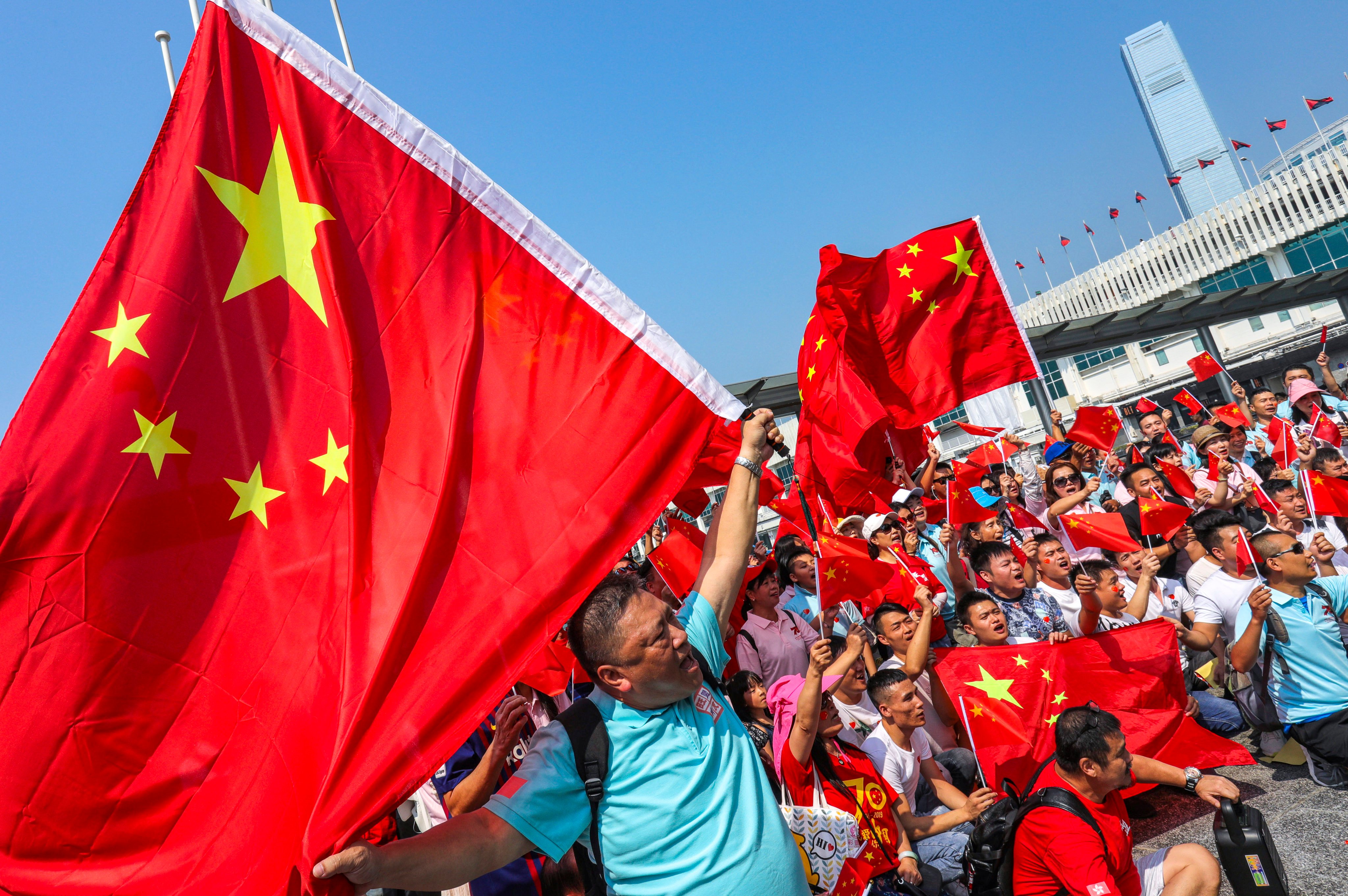People wave the national flag at Star Ferry Pier in Tsim Sha Tsui on October 1, 2019. Photo: May Tse
