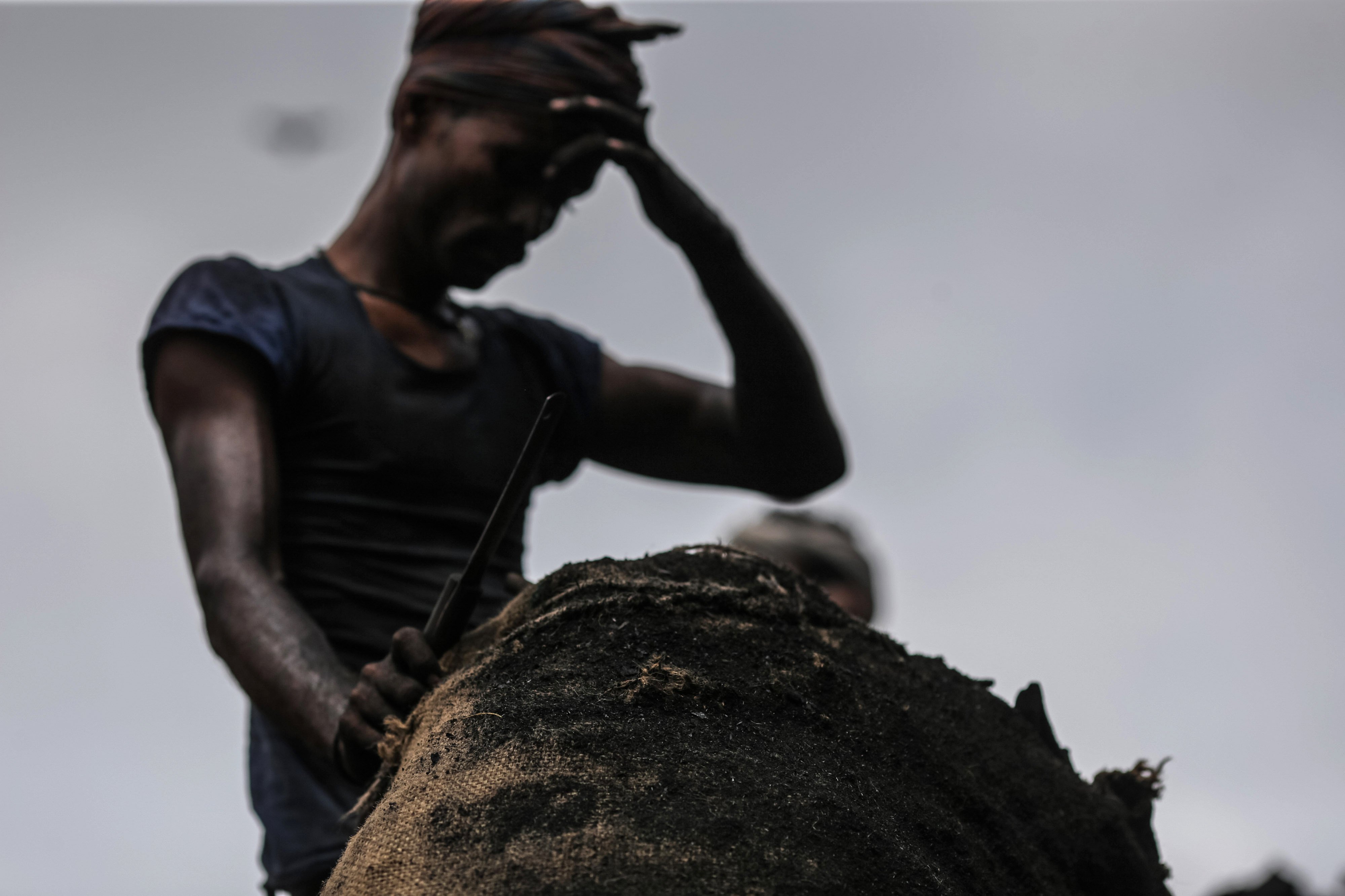A worker unloads a sack of charcoal from a truck at a wholesale market in Mumbai on August 9. Photo: Bloomberg