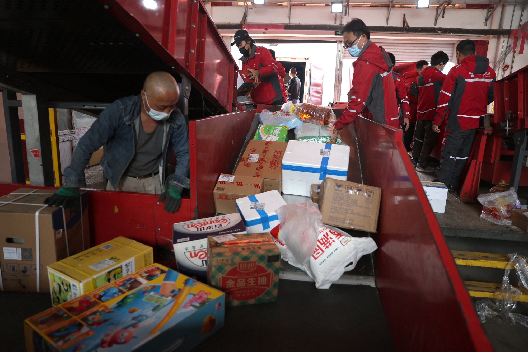 Employees wearing masks move goods on a conveyor belt at JD.com’s smart logistics centre on April 28, 2022, following a Covid-19 outbreak in Beijing. Photo: Reuters