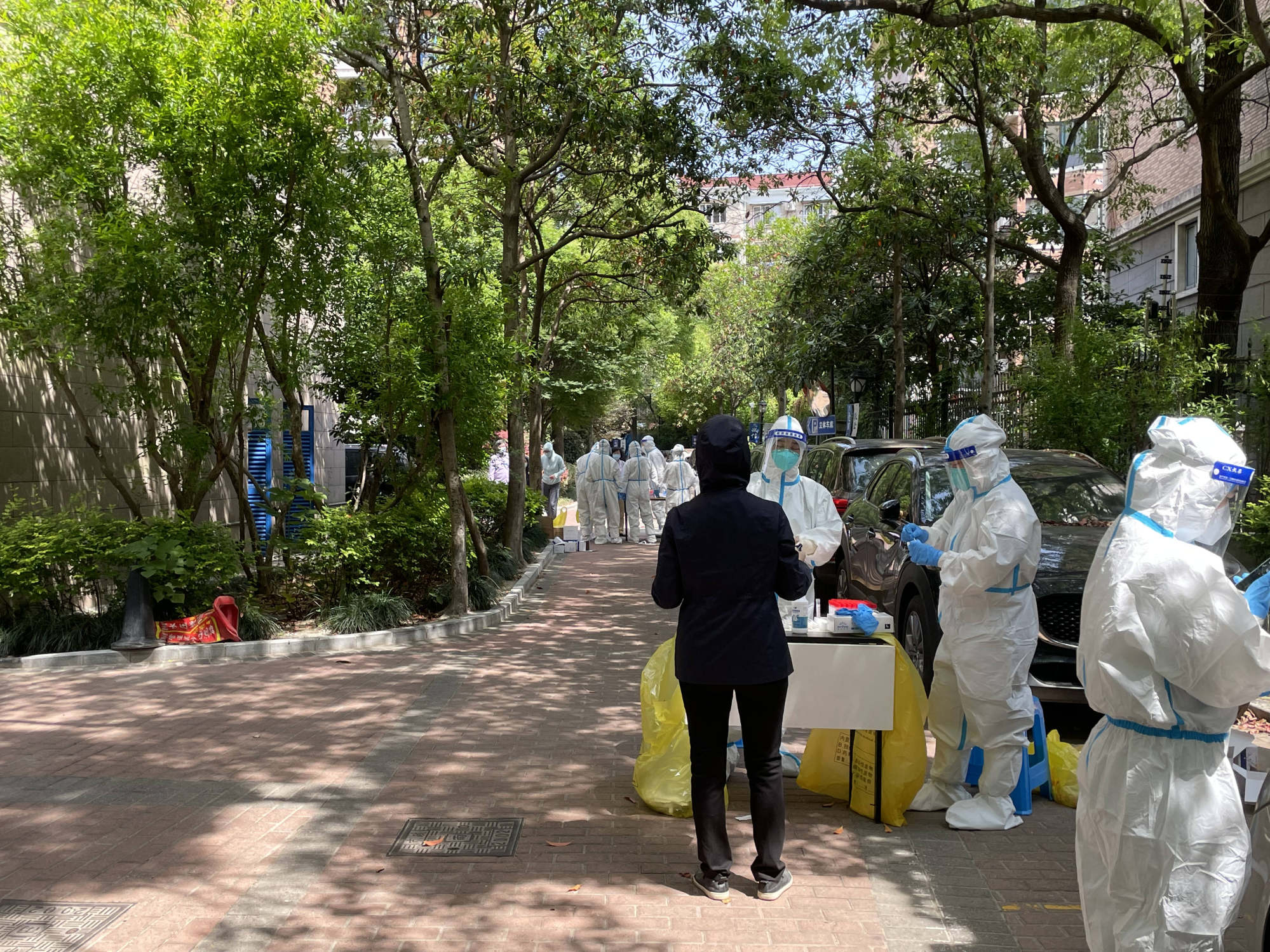 Medical workers and volunteers in white hazmat suits, known locally as dabai or “big white”, conduct coronavirus tests in a Shanghai residential compound. Photo: SCMP/ Tracy Qu