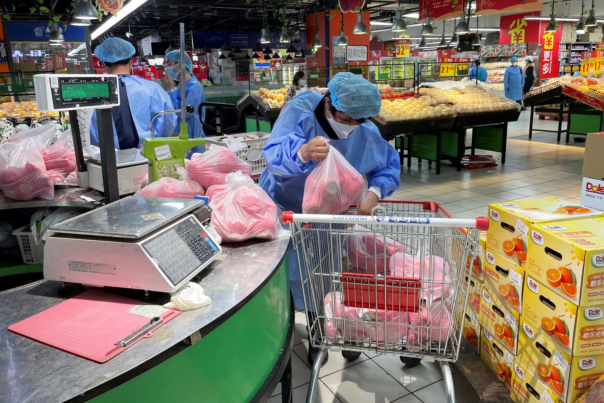 A worker in a protective suit sorts vegetables in a shopping trolley, at a reopened Carrefour supermarket amid the coronavirus disease (COVID-19) outbreak in Shanghai on May 19, 2022. Photo: Reuters