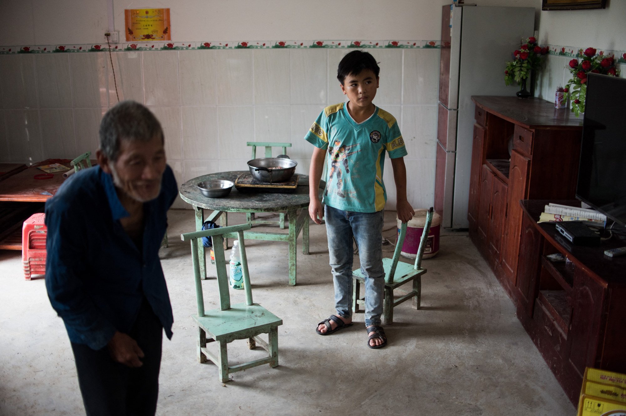 Liang Zhaolu (the child) tends to his grandfather’s rice fields during weekends home from boarding school. Photo: AFP