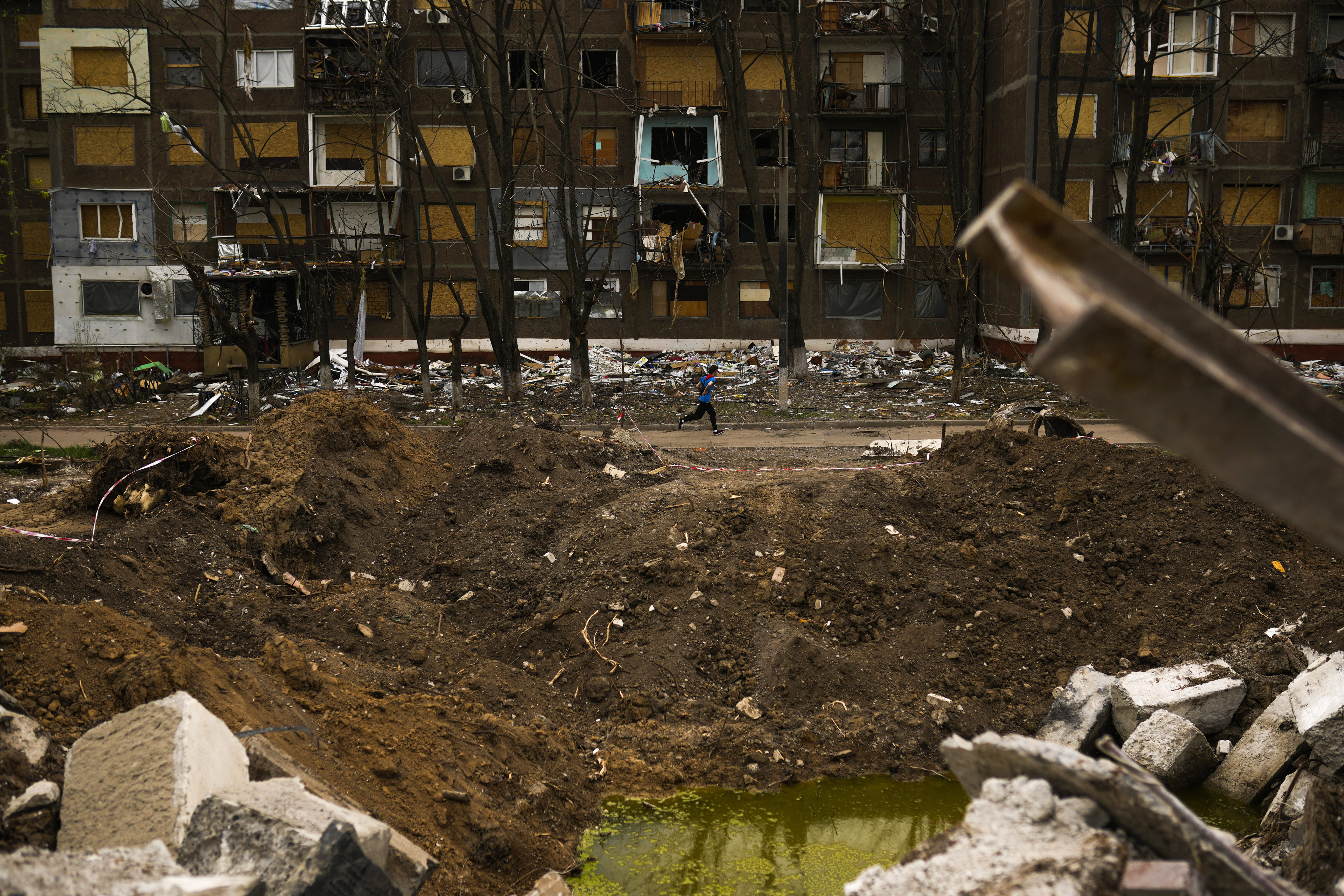 A jogger passes by a crater caused by a Russian strike opposite a block of flats in Kramatorsk, eastern Ukraine, on May 21. Photo: AP