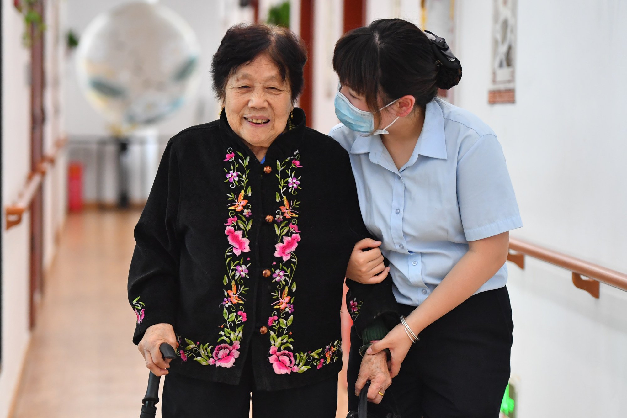 A nursing worker helps an elderly woman walk at an elderly care service centre in Yuhu District of Xiangtan City in Hunan Province on May 17, 2022. Photo: Xinhua