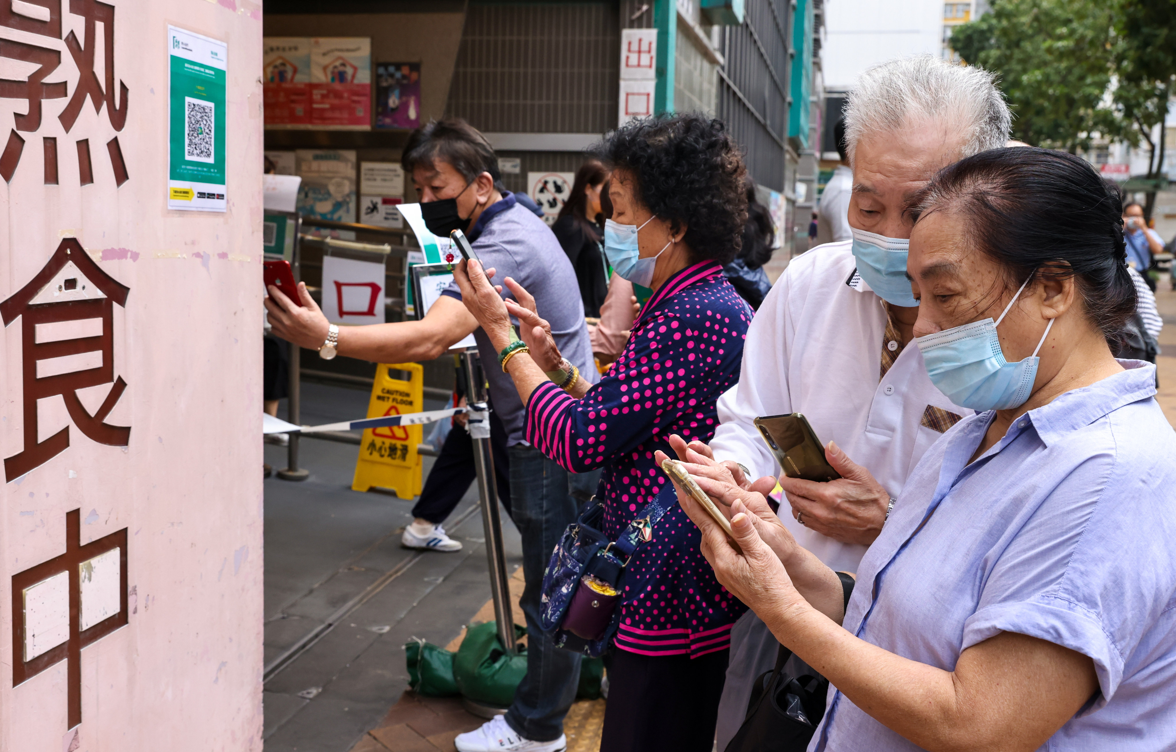Elderly residents use the “Leave Home Safe” app on their smartphones to scan a QR code to enter a market in Tai Po. Photo: K. Y. Cheng