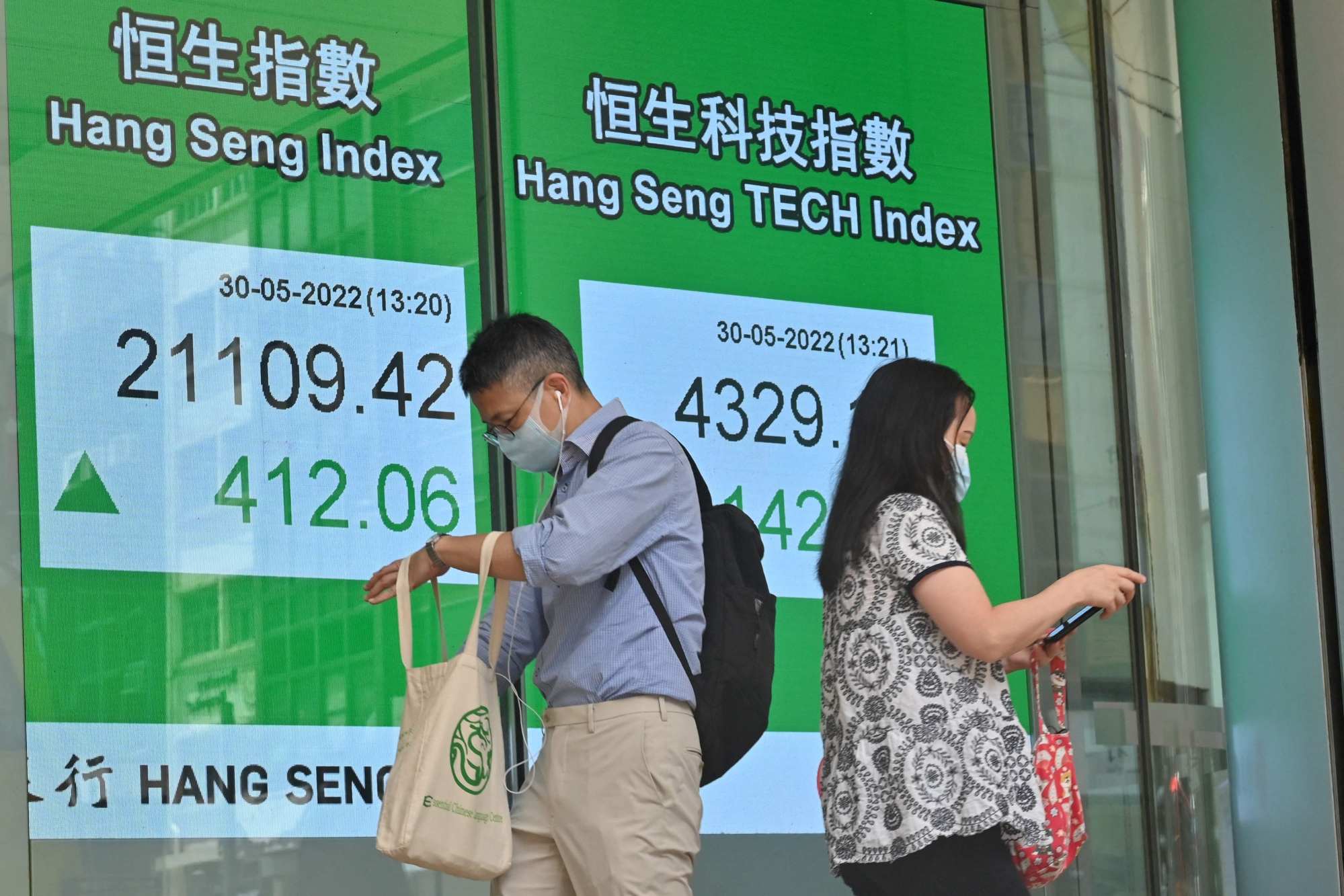 Pedestrians walk past a sign showing the Hang Seng Index in Hong Kong on May 30. Photo: AFP