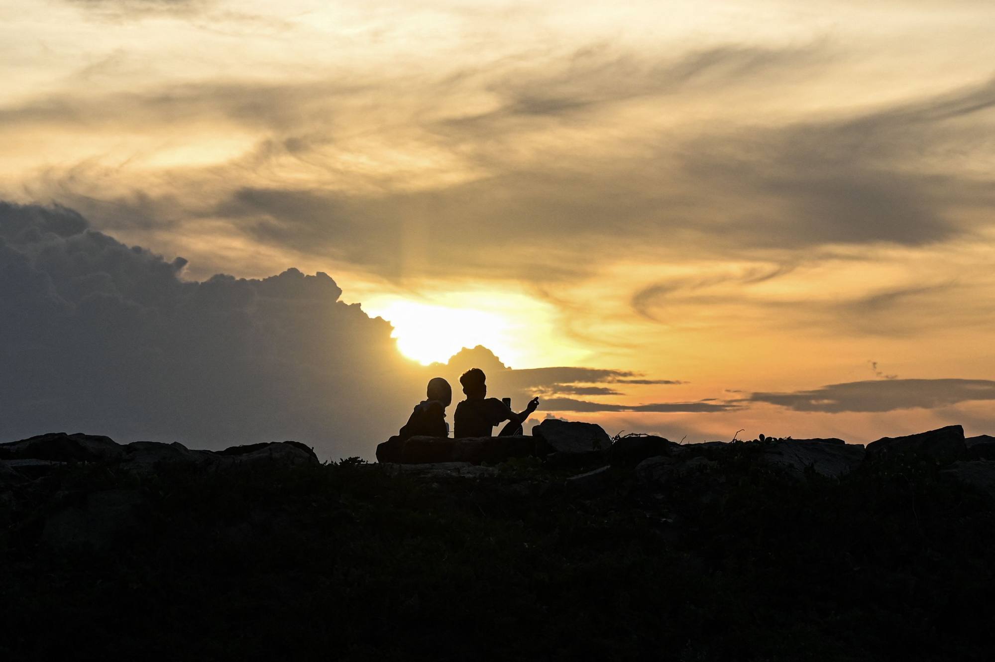 A couple take pictures at sunset on a Malaysian beach. Photo: AFP