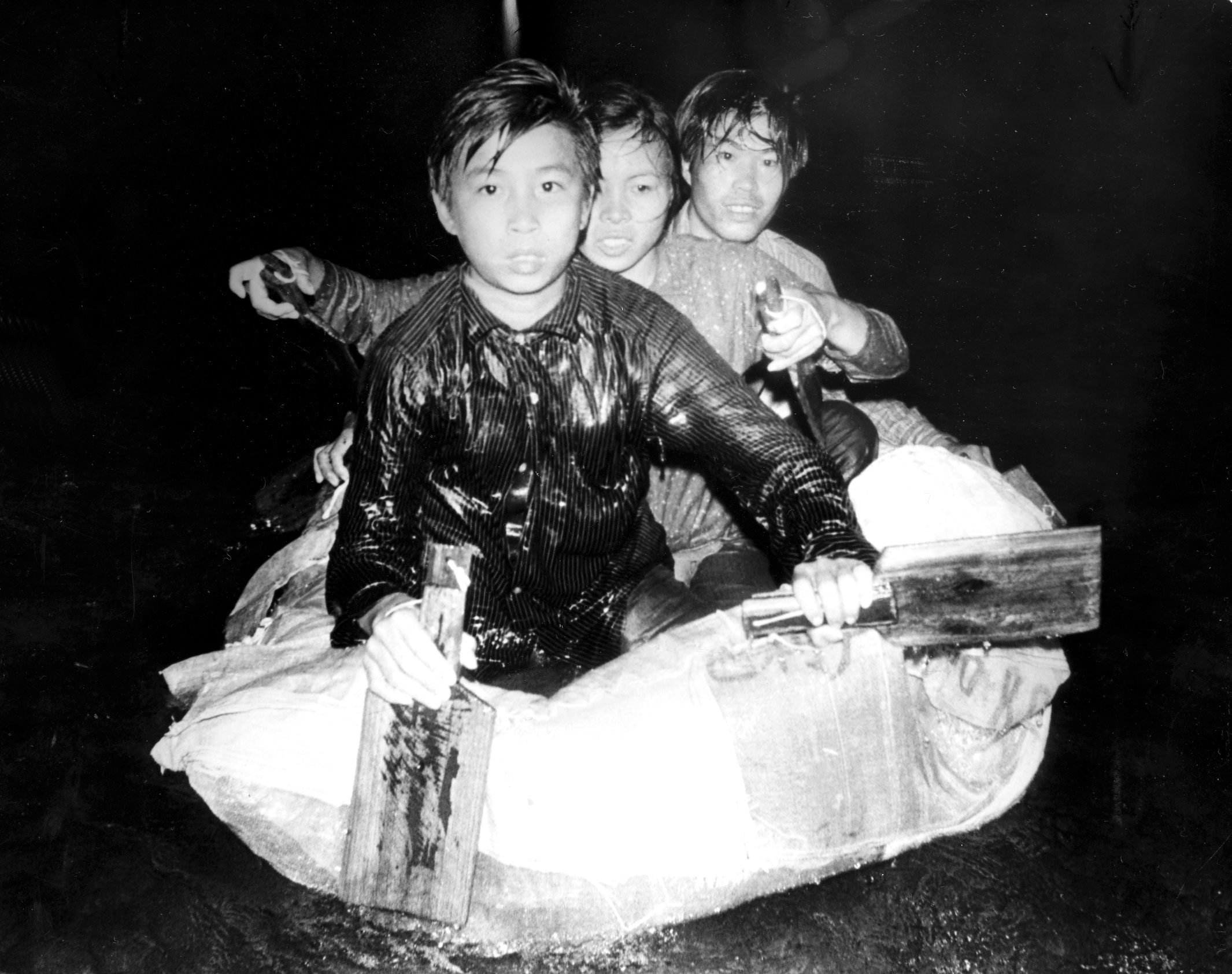 Three illegal immigrants stare at their captors moments after a Marine Police patrol spotted them in Deep Bay, November 11, 1979. Their raft is made of inflatable plastic cushions swen together and covered with plastic bags. 11NOV79 SCMP/ C. Y. Yu