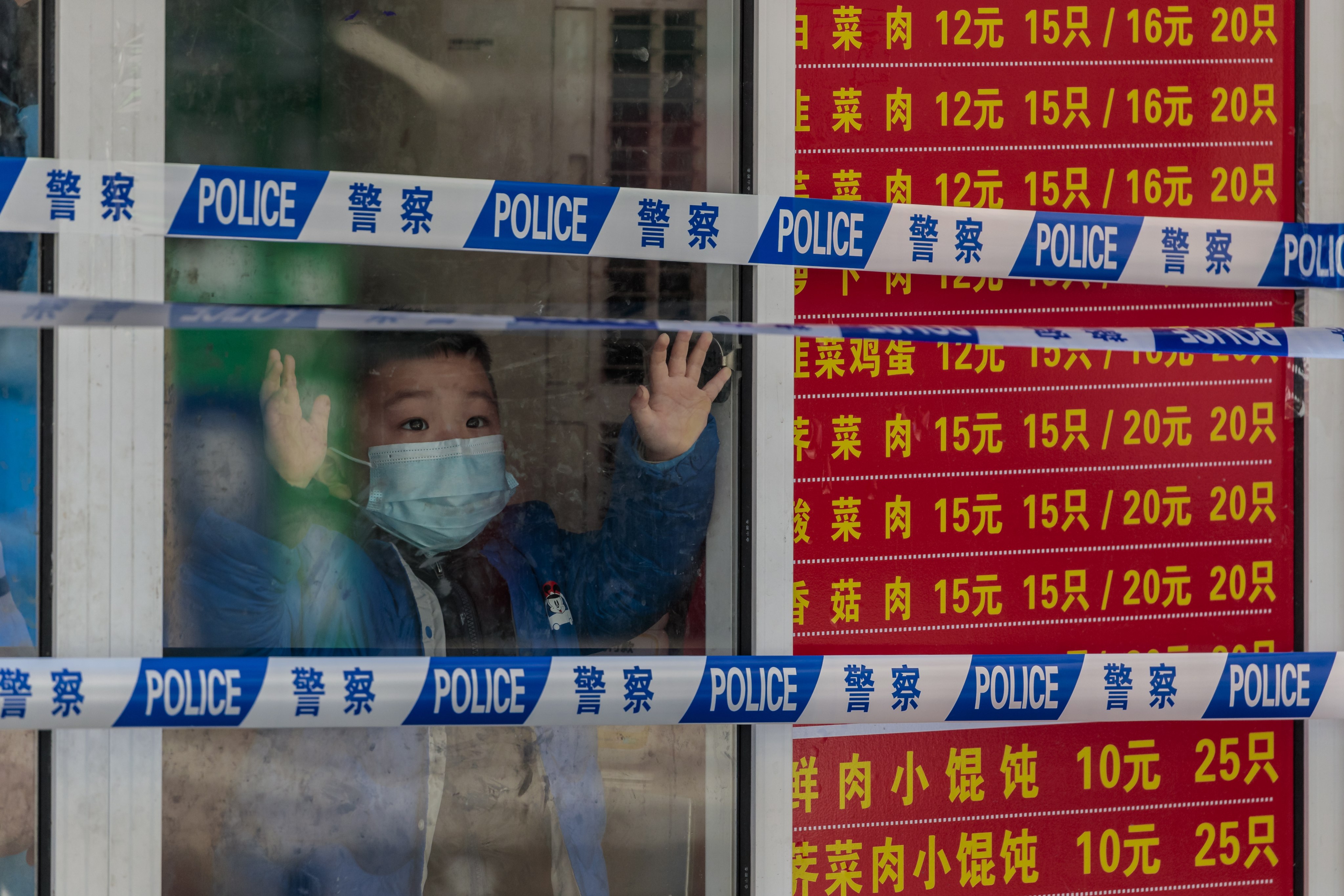 A boy looks through a shop window in a locked-down restaurant in Shanghai in late March.Photo: EPA-EFE
