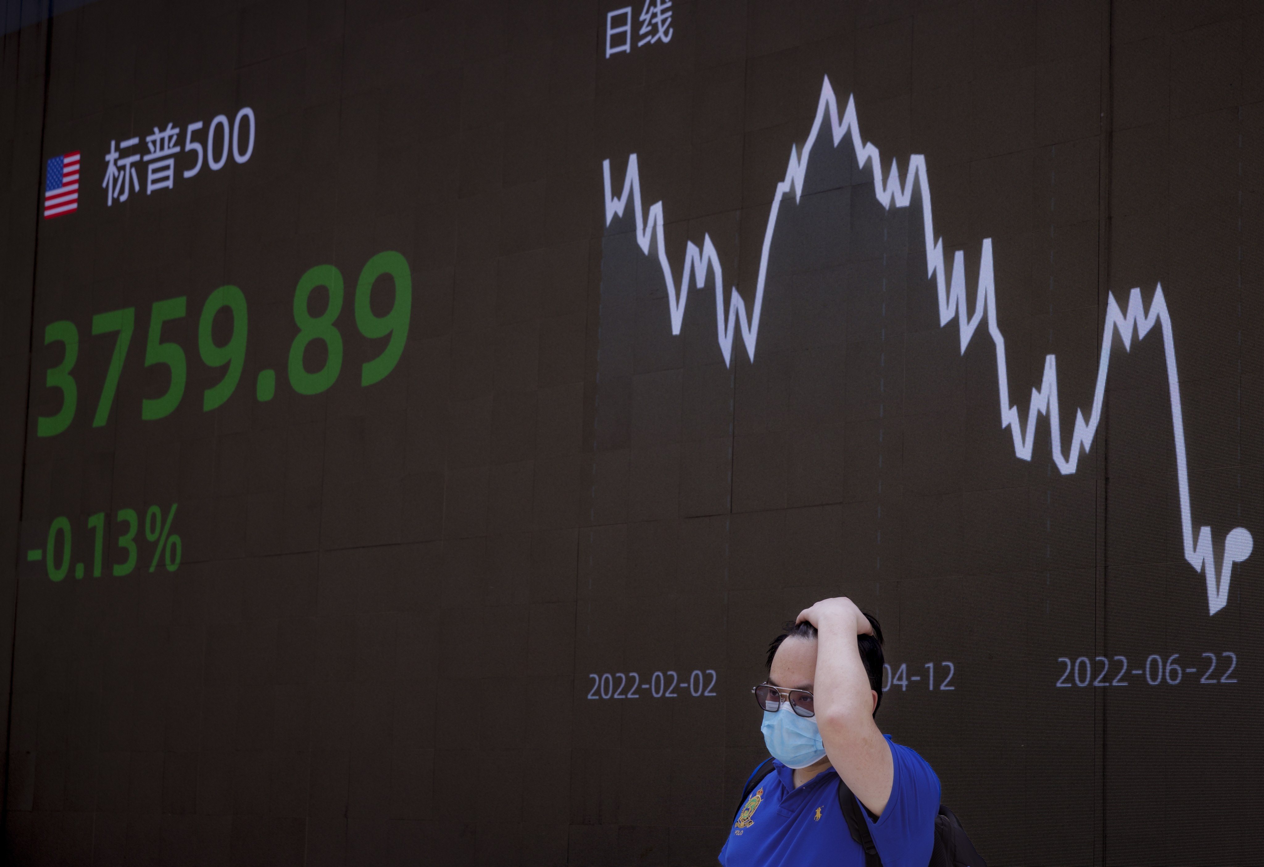 A man stands in front of a large screen showing economic and stock exchange updates in Shanghai on June 23. Photp: EPA-EFE