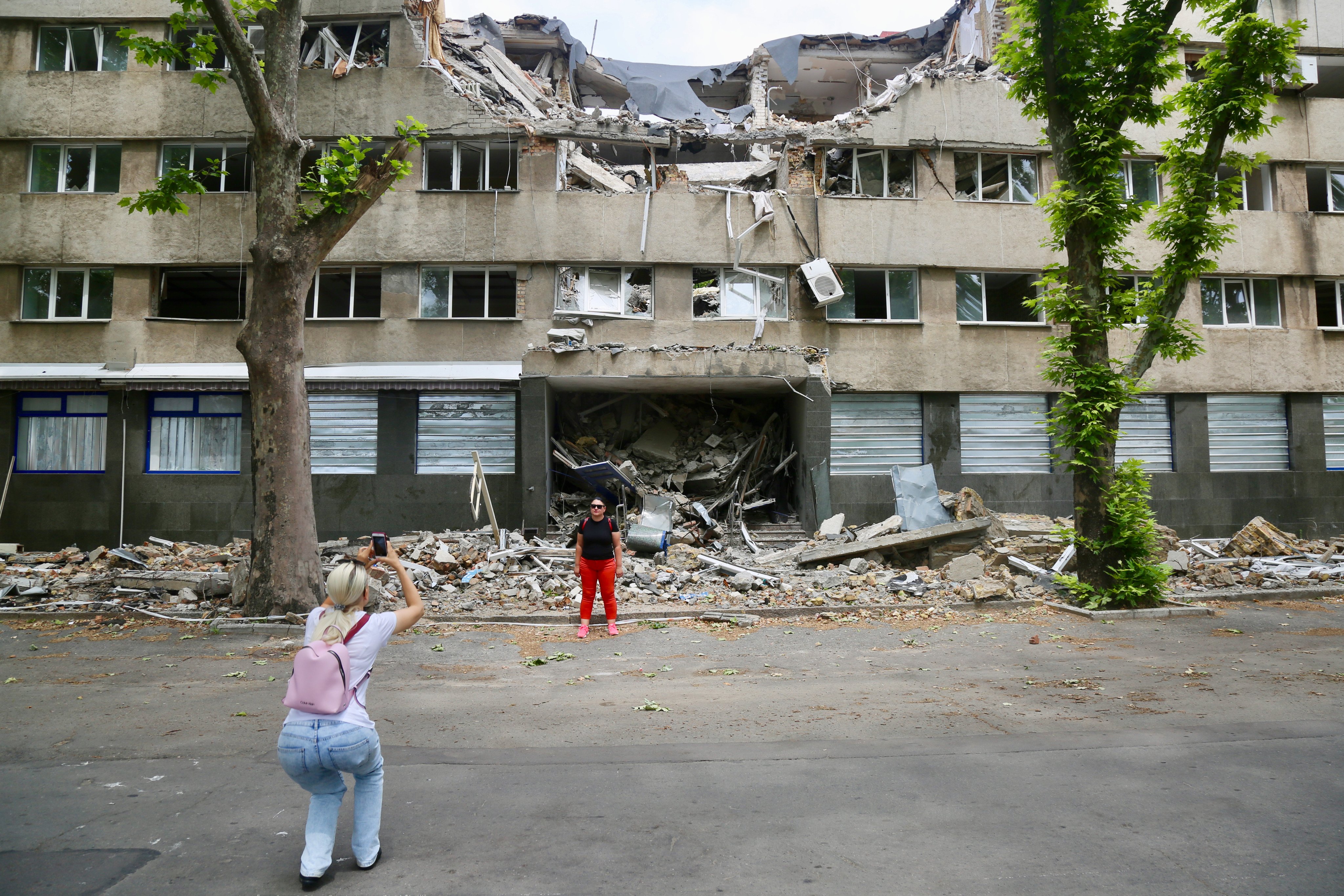 War tourists take photos outside a bombed out building in Mykolaiv, a city about 130km from Odesa, in Ukraine. Photo: Ian Neubauer