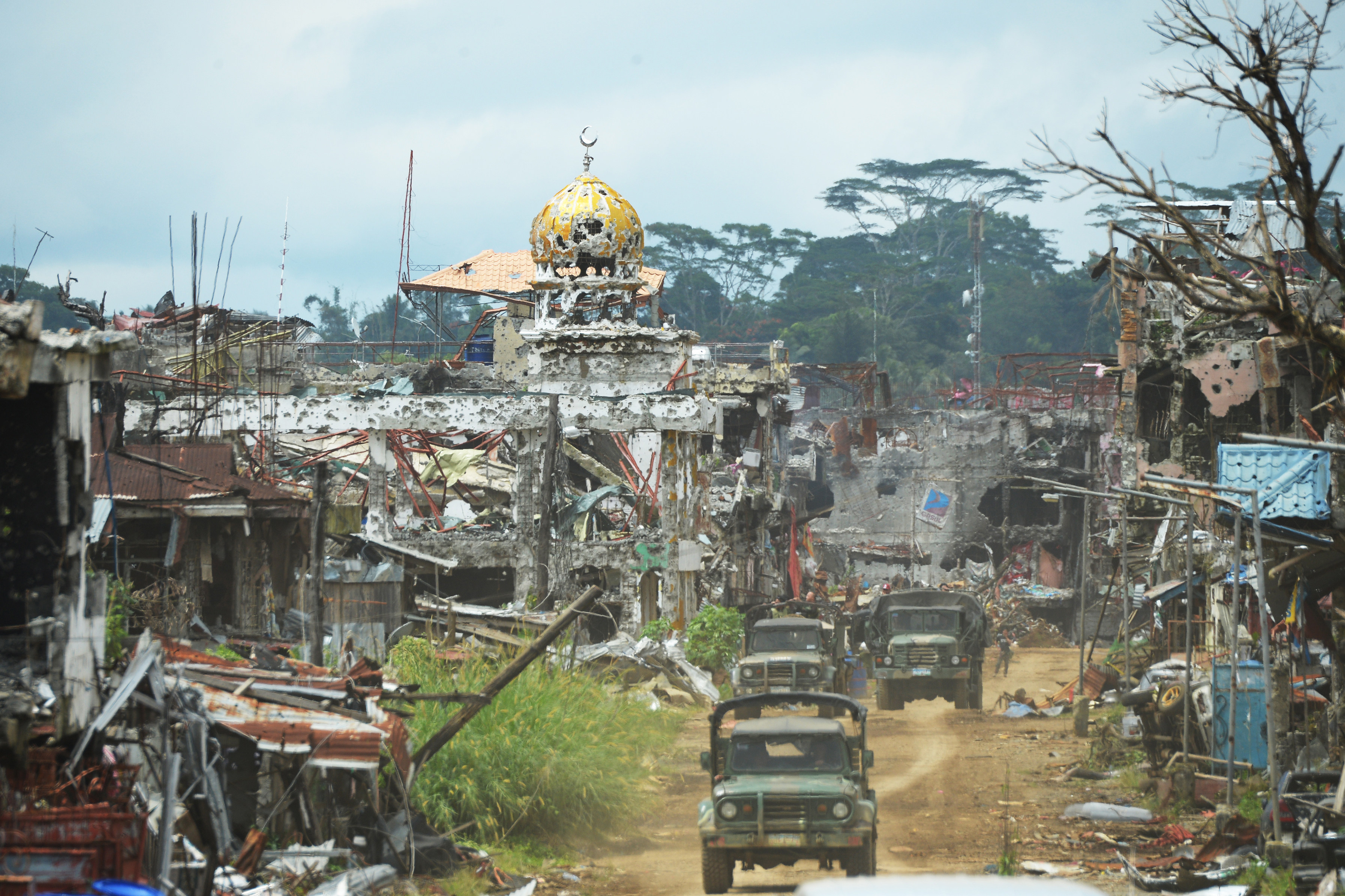 Military trucks drive past destroyed buildings and a mosque in Marawi in 2017. Photo: AFP