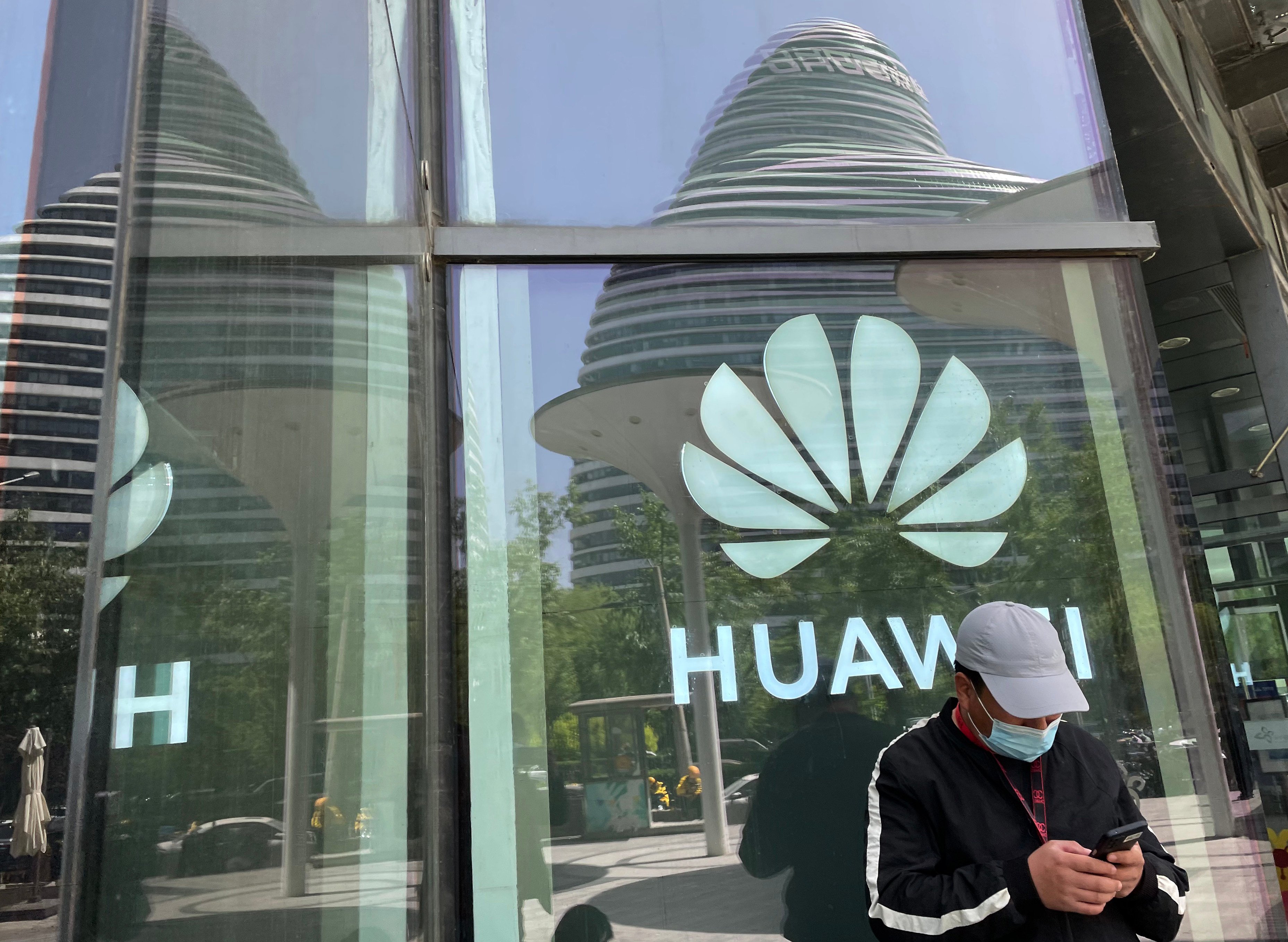 A man reads from his mobile phone in front of Huawei’s logo in Beijing on April 27. Photo: Simon Song