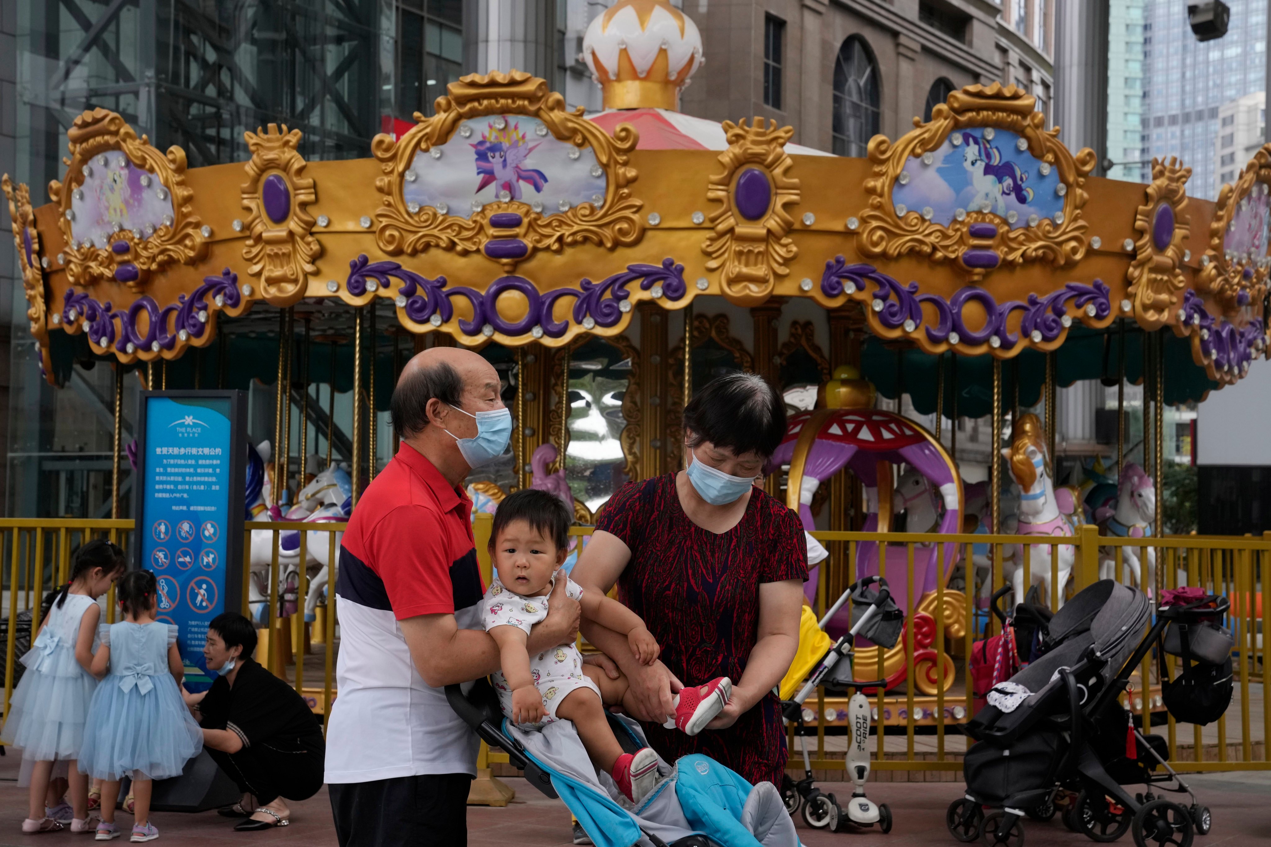 Elderly residents tend to a child near a carousel at a shopping centre in Beijing. Photo: AP