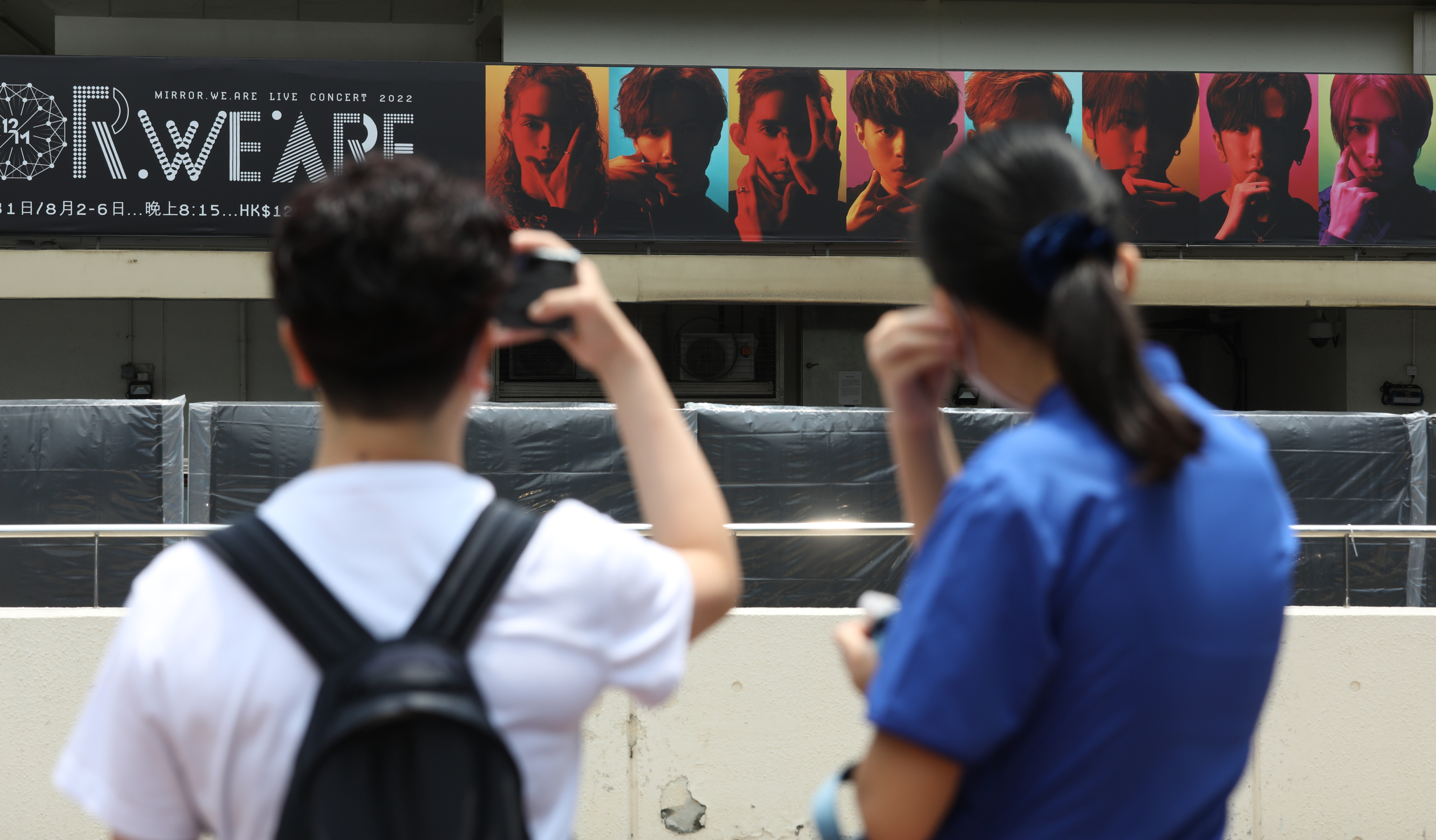 Fans of Canto-pop boy band Mirror take pictures of a billboard featuring the group outside Hong Kong Coliseum. Photo: Yik Yeung -man