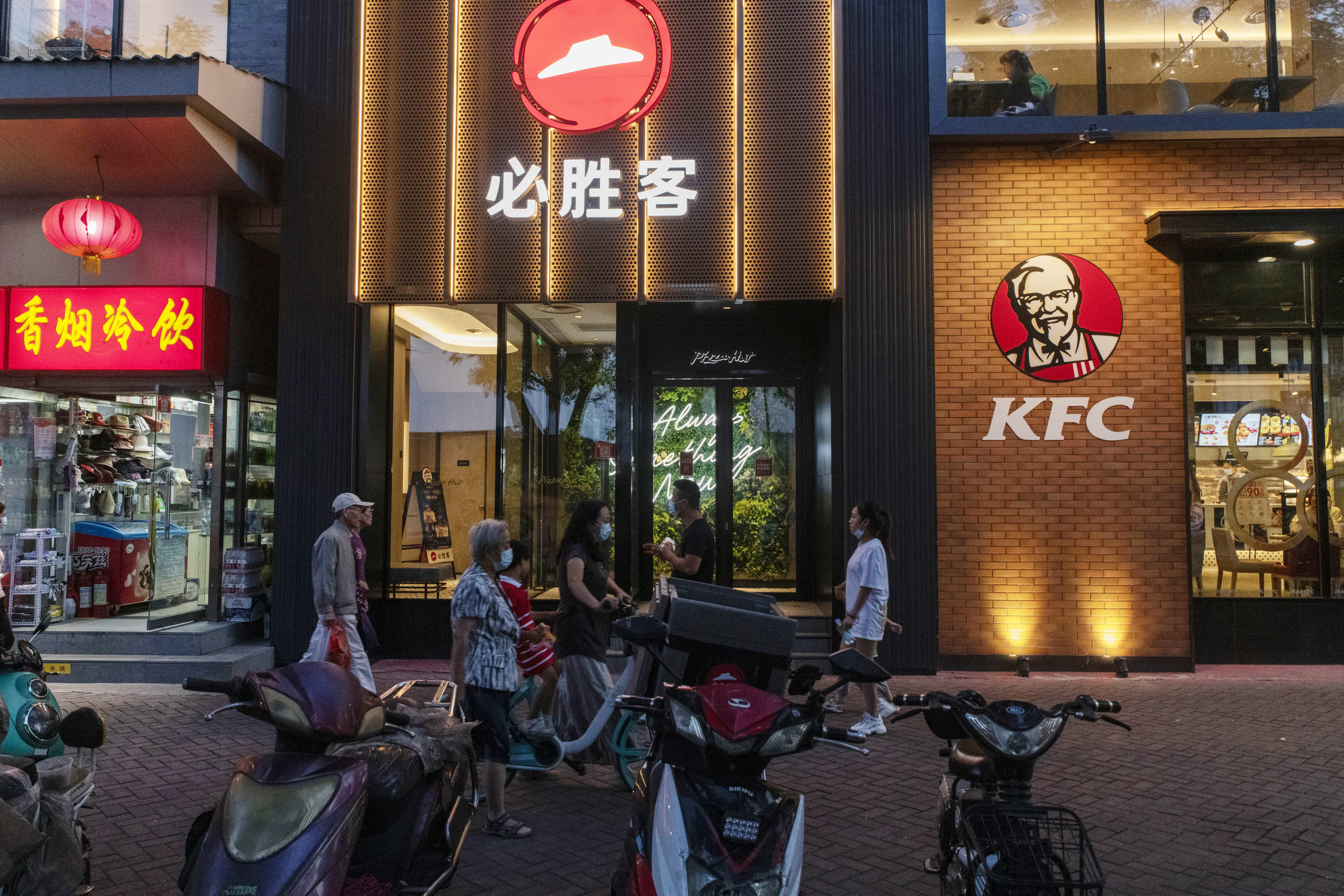 Pedestrians walk past a Pizza Hut restaurant and a KFC restaurant, both operated by Yum China, in Beijing. Photo: Bloomberg