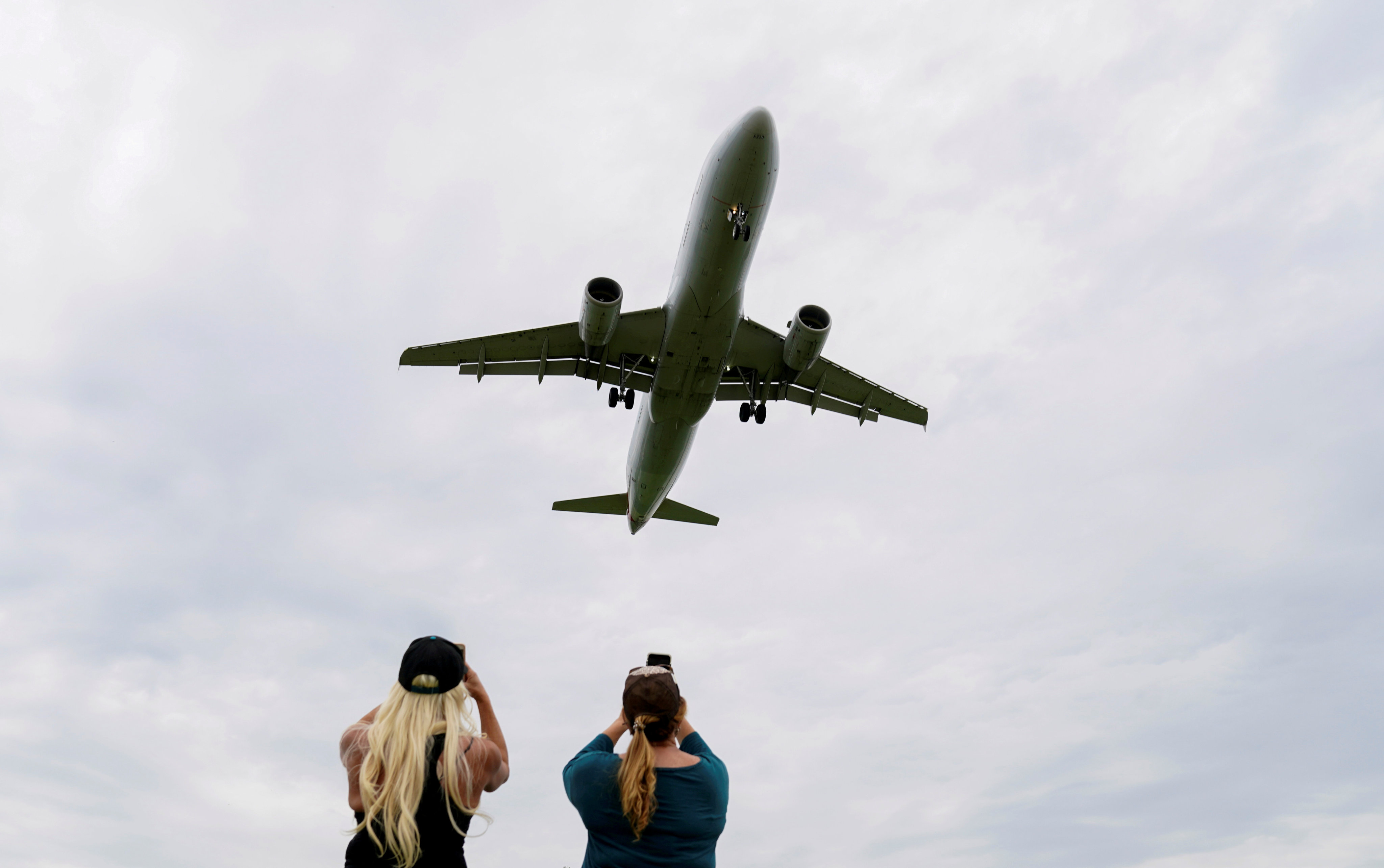 Women photograph a plane landing at an airport in Washington in April 2020. Photo: Reuters 