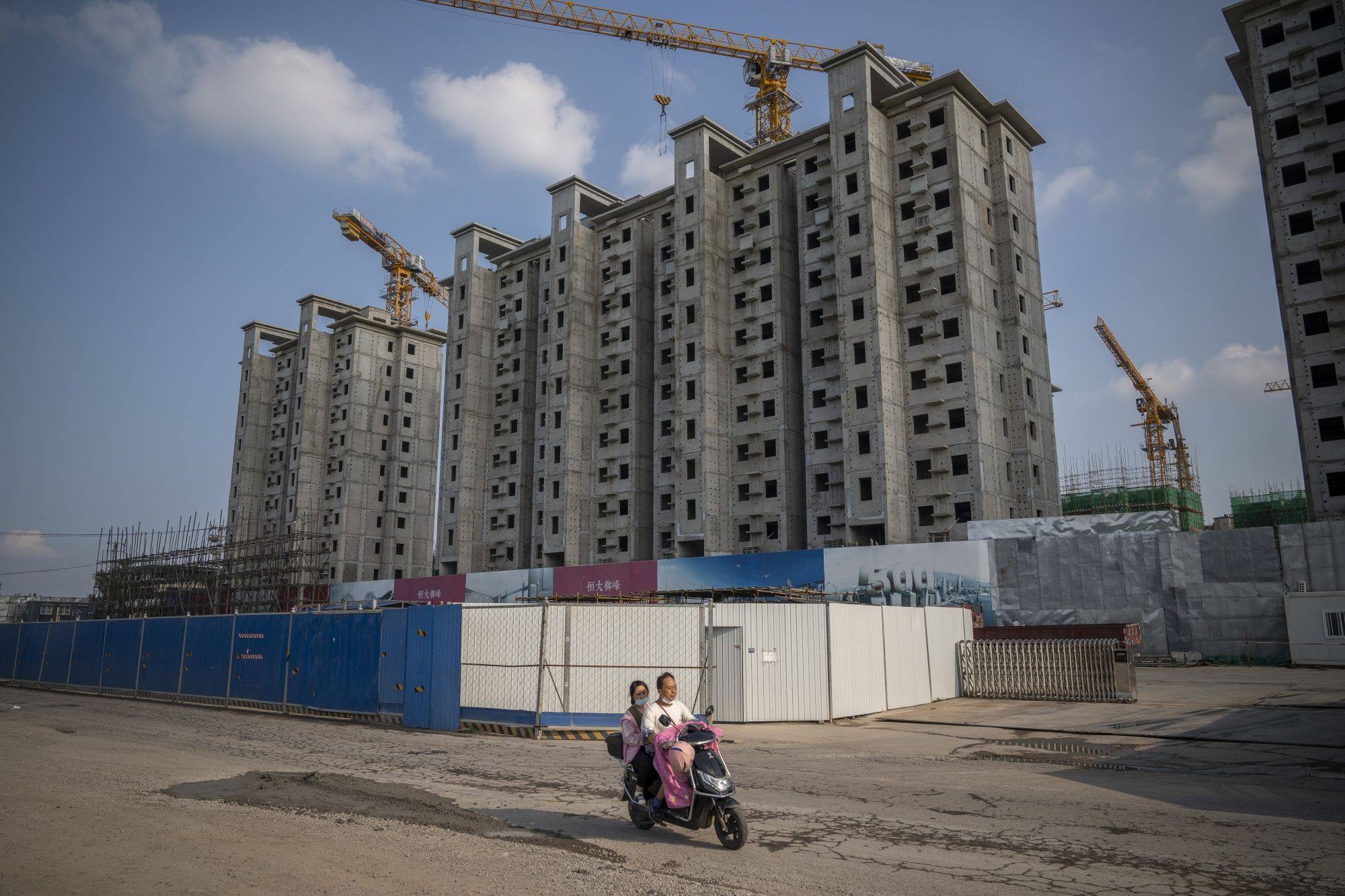 A man and a woman ride past an unfinished China Evergrande residential development in Beijing, on July 29. The war in Ukraine, resurgent inflation and a slowdown in China’s construction sector have all contributed to a volatile first half of 2022 for commodity prices. Photo: Bloomberg