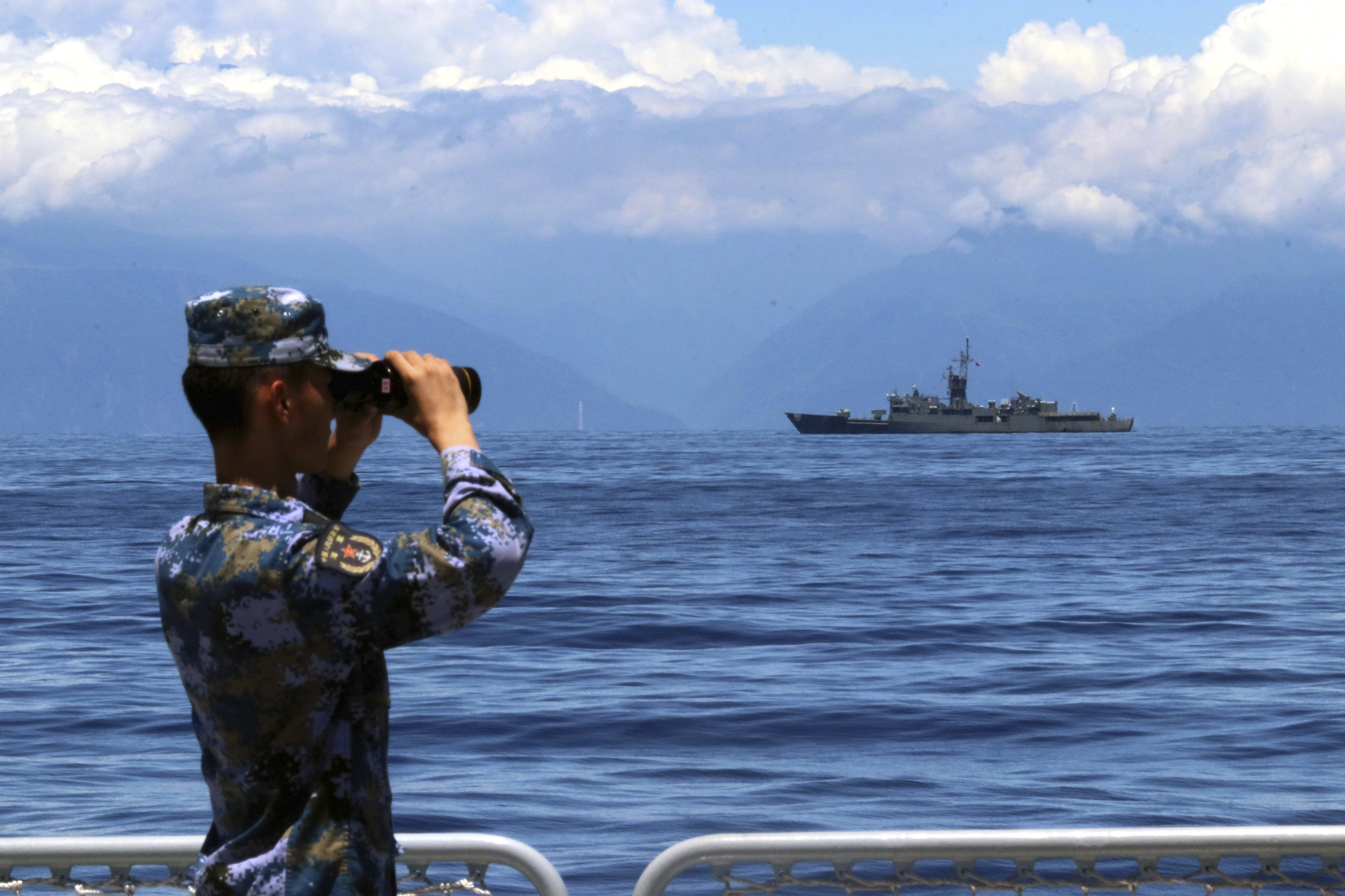 A People’s Liberation Army soldier looks on during military exercises in and over waters around Taiwan on August 5. A Taiwan frigate is seen in the background. Photo: Xinhua via AP