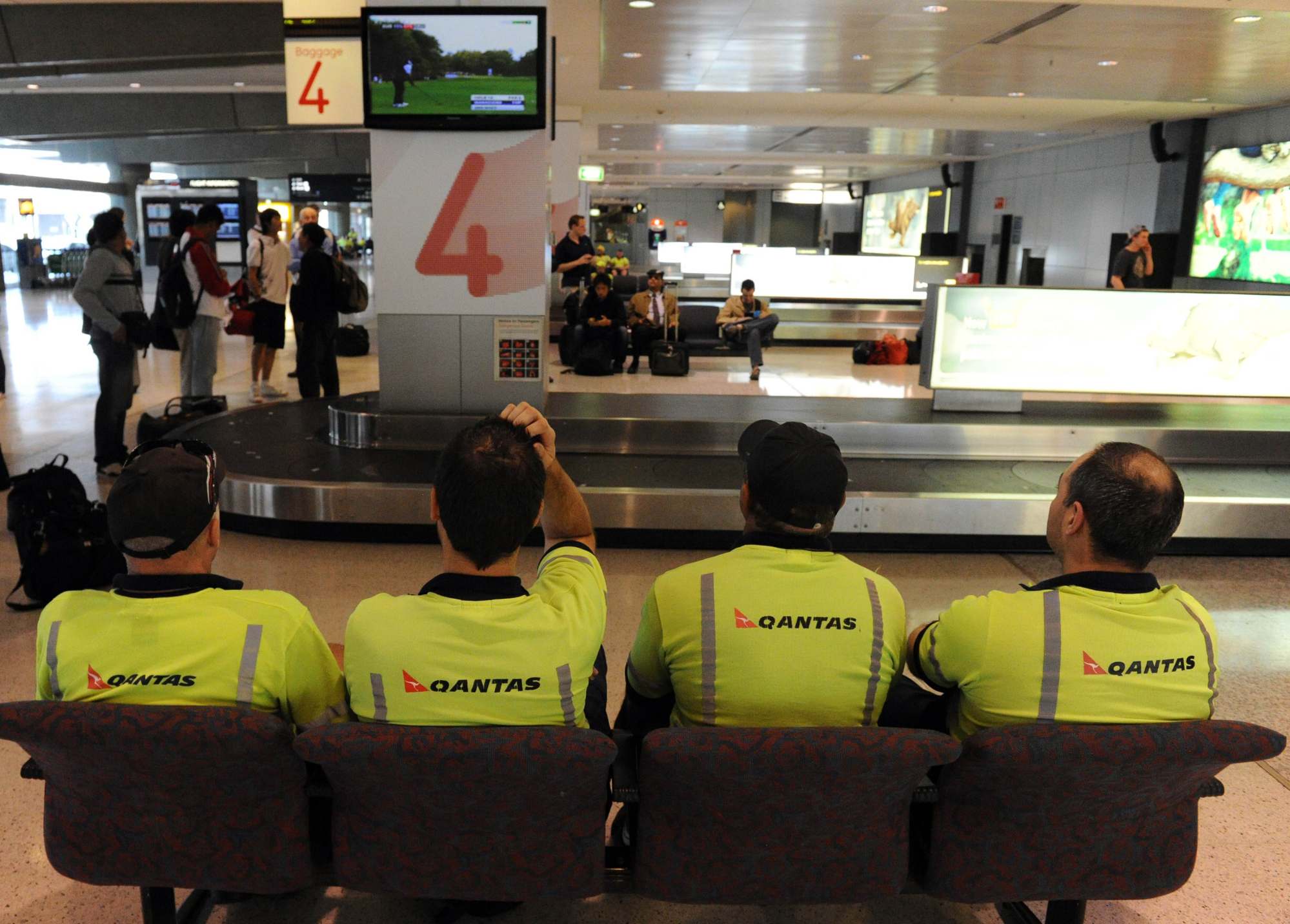 Qantas baggage handlers, seated, at Sydney International Airport. Photo: AFP