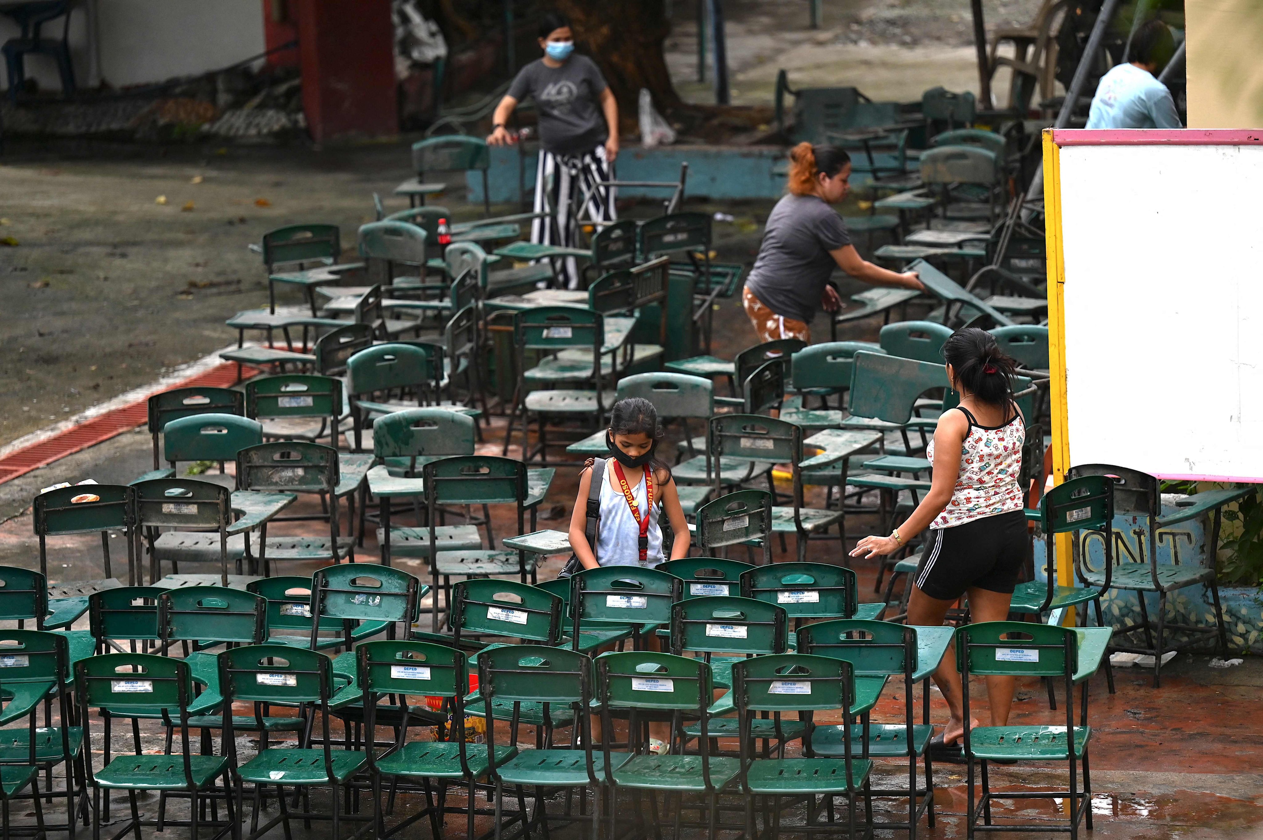 Volunteers scrub chairs as they clean classrooms at a school in Manila, Philippines, on August 5. Photo: AFP